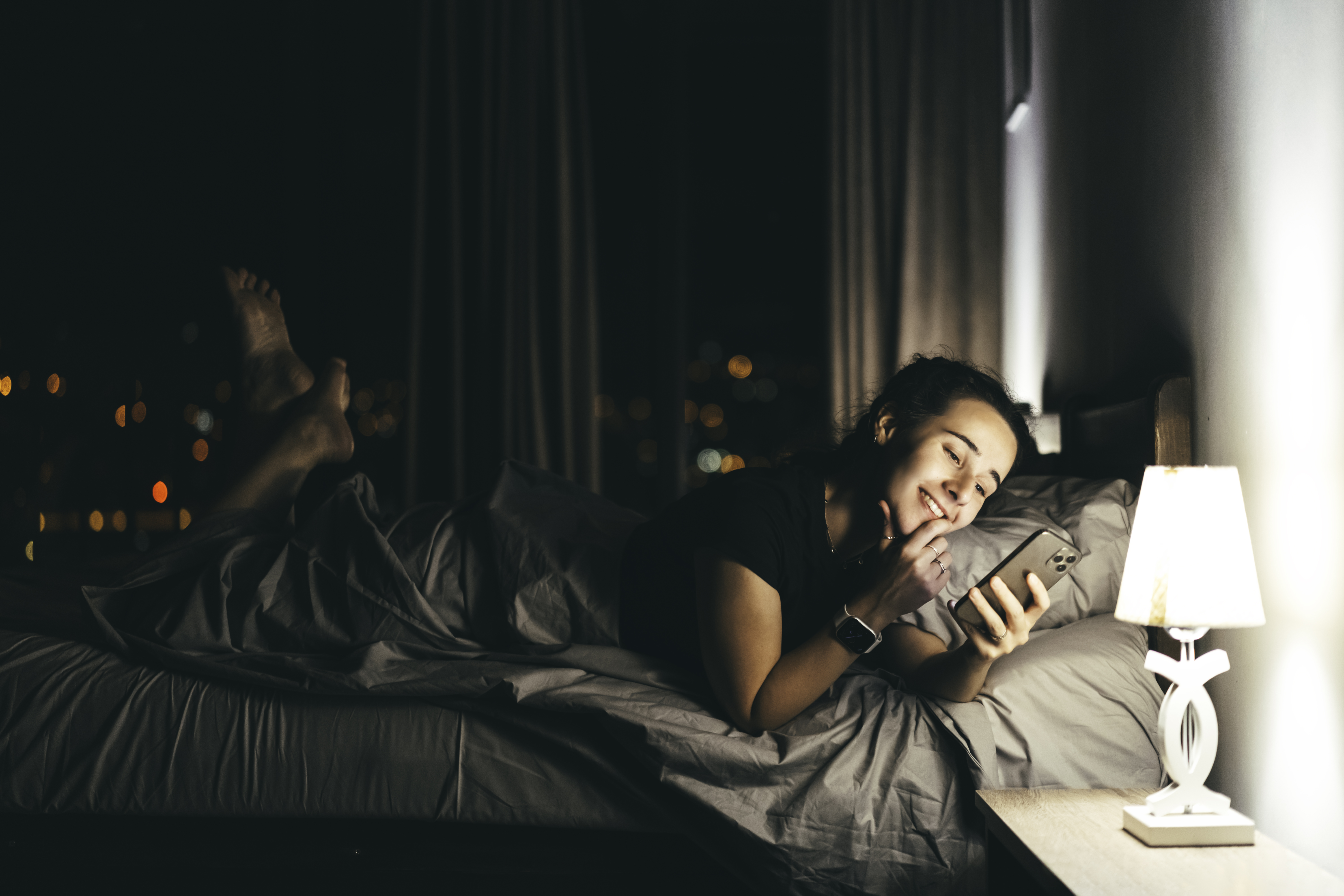 Personne heureuse allongée dans son lit et tenant son téléphone | Source : Getty Images