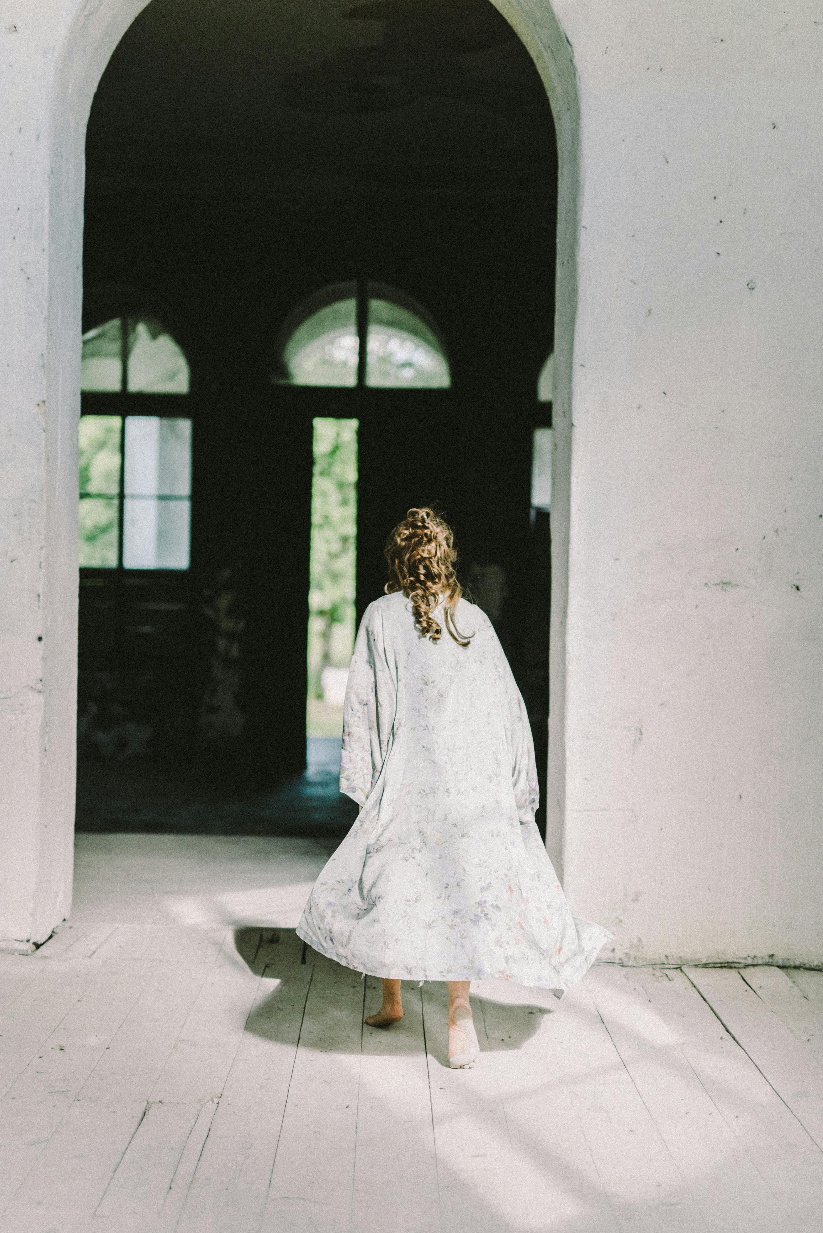 Vue arrière d'une femme marchant dans une porte en arc | Source : Pexels