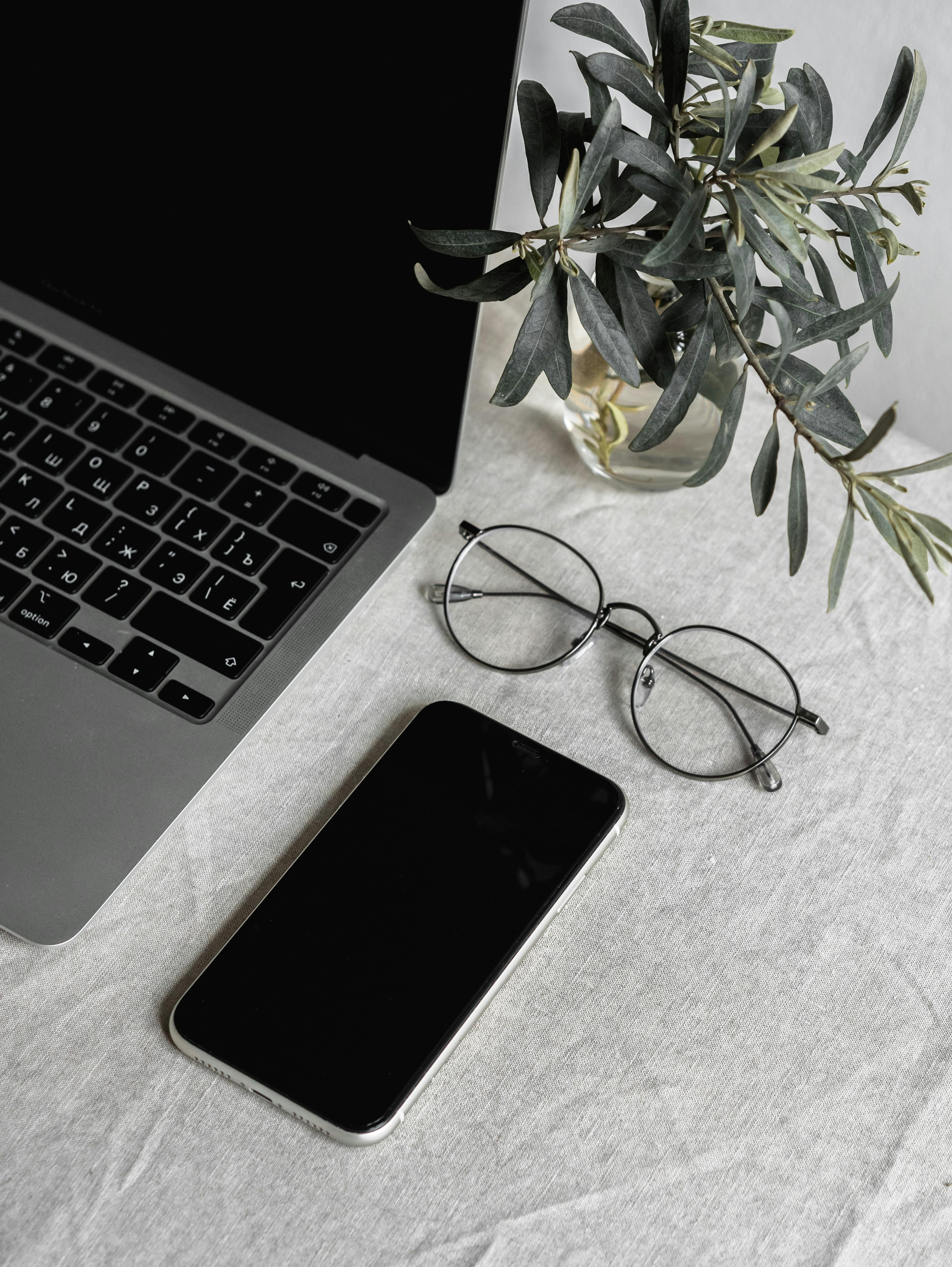 Un téléphone portable, des lunettes et un ordinateur portable sur une table | Source : Pexels