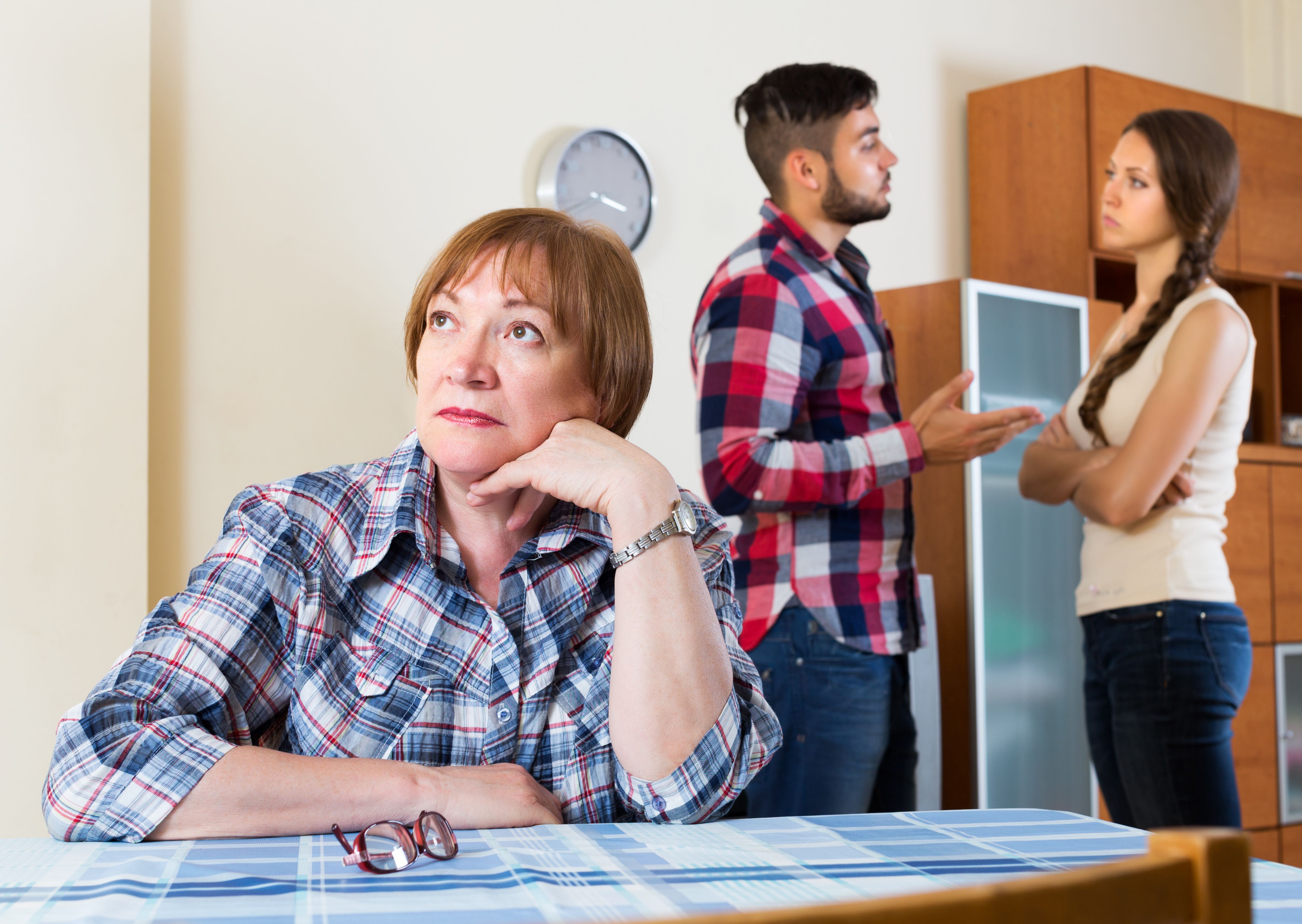 Une femme sur la table tandis que deux personnes parlent derrière elle. | Source : Getty Images