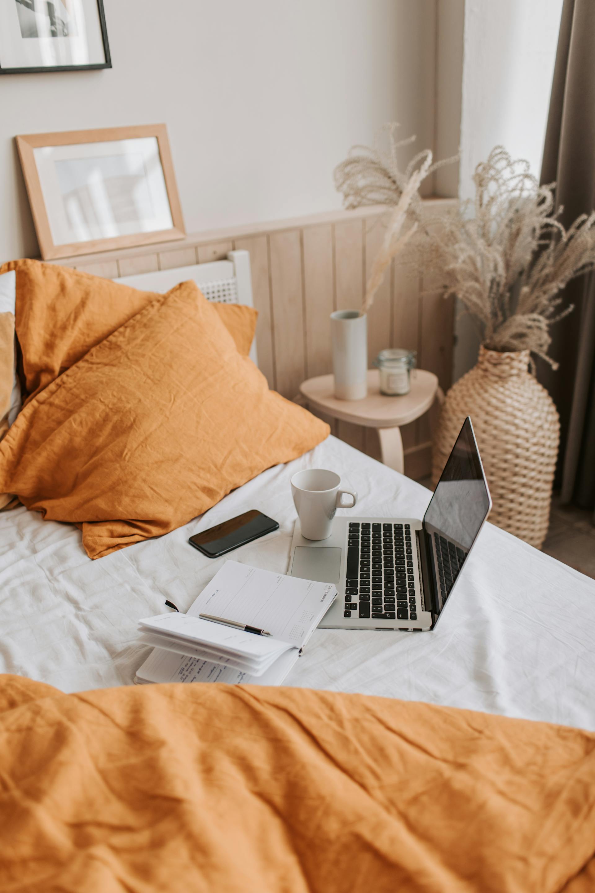 Une tasse de café et un ordinateur portable sur un lit | Source : Pexels
