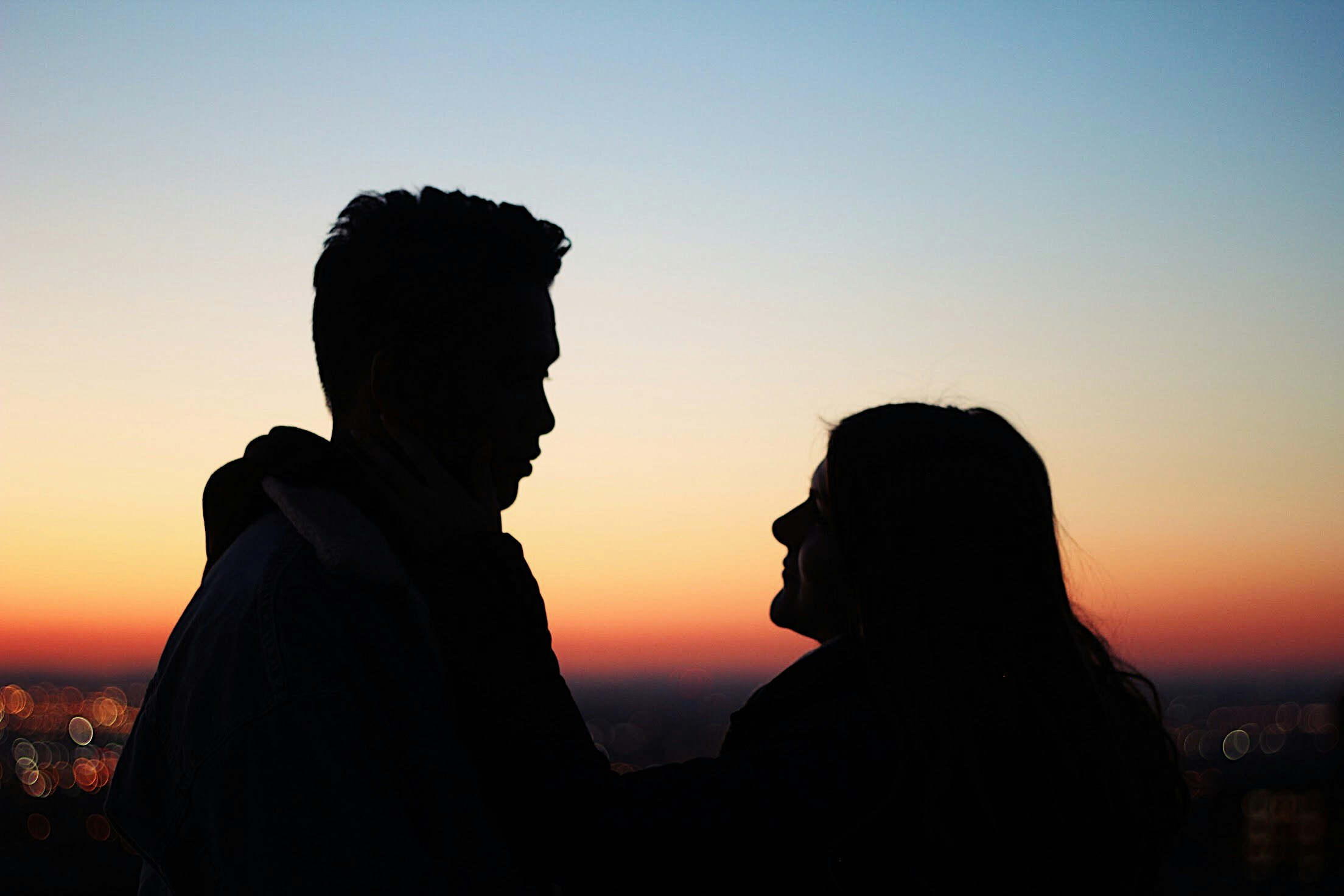Silhouette d'un homme et d'une femme en train de parler | Source : Unsplash