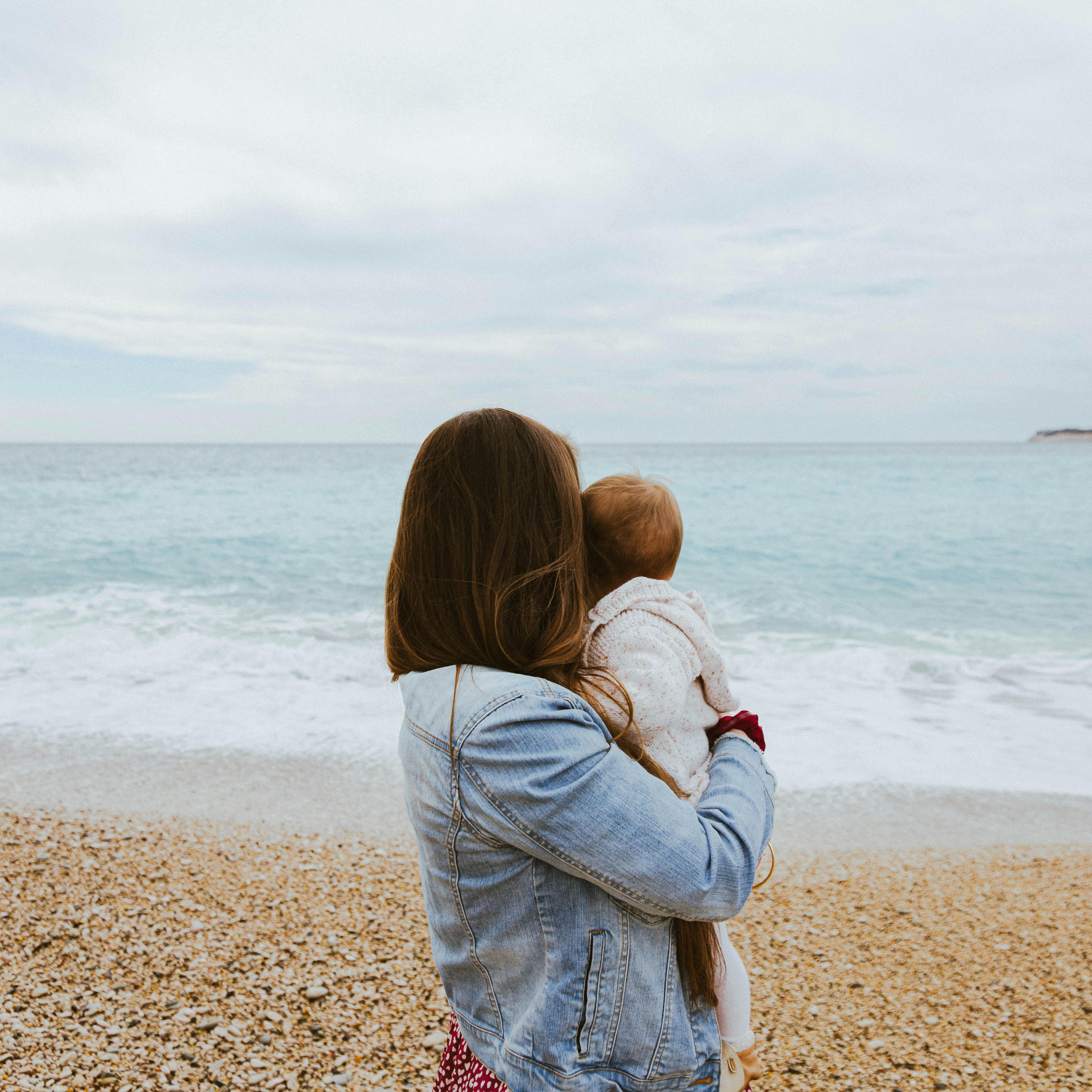 Une femme tenant son bébé à la plage | Source : Pexels