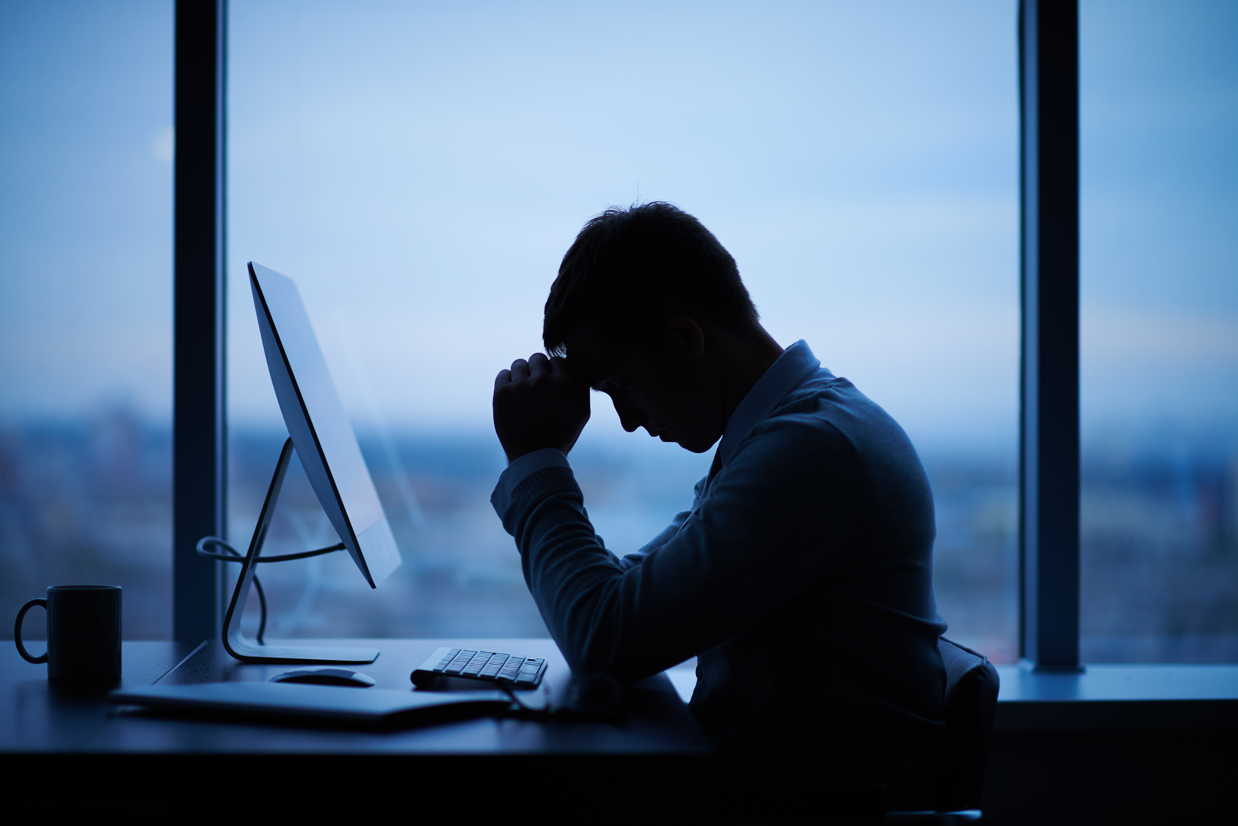 Homme fatigué assis devant un ordinateur au bureau | Source : Shutterstock
