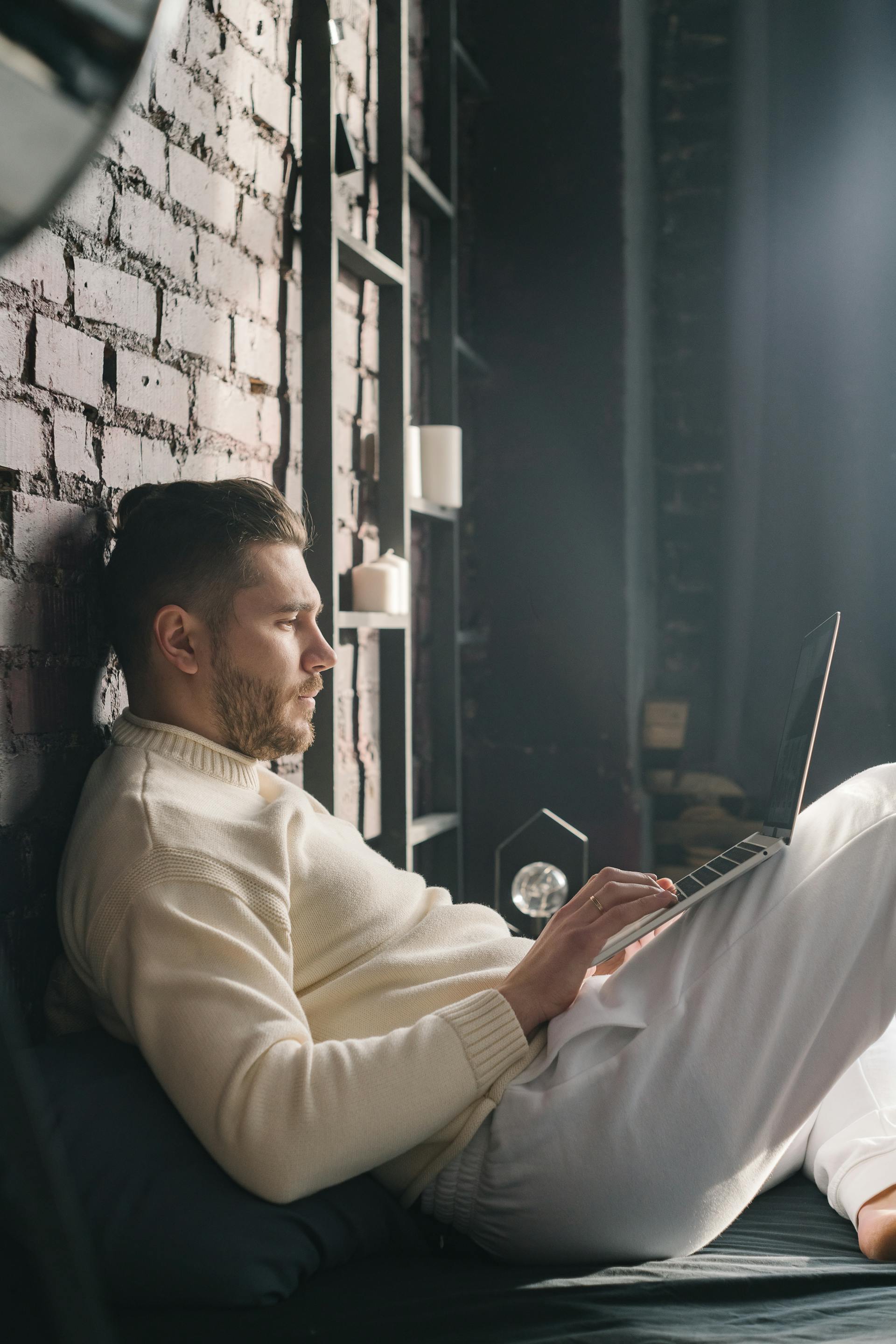Un homme assis sur le lit avec son ordinateur portable | Source : Pexels