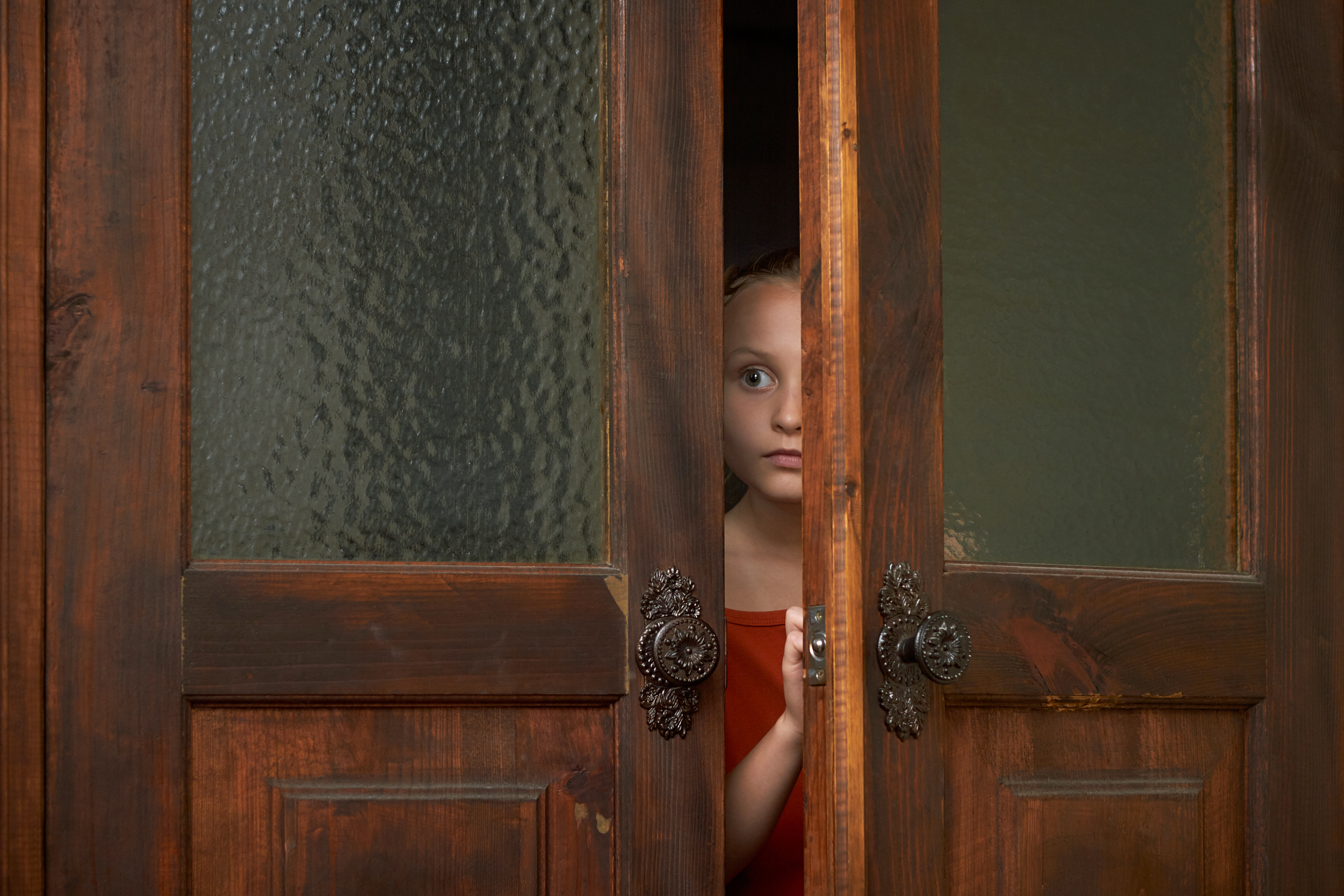 Une petite fille effrayée qui regarde par la fente de la porte | Source : Shutterstock