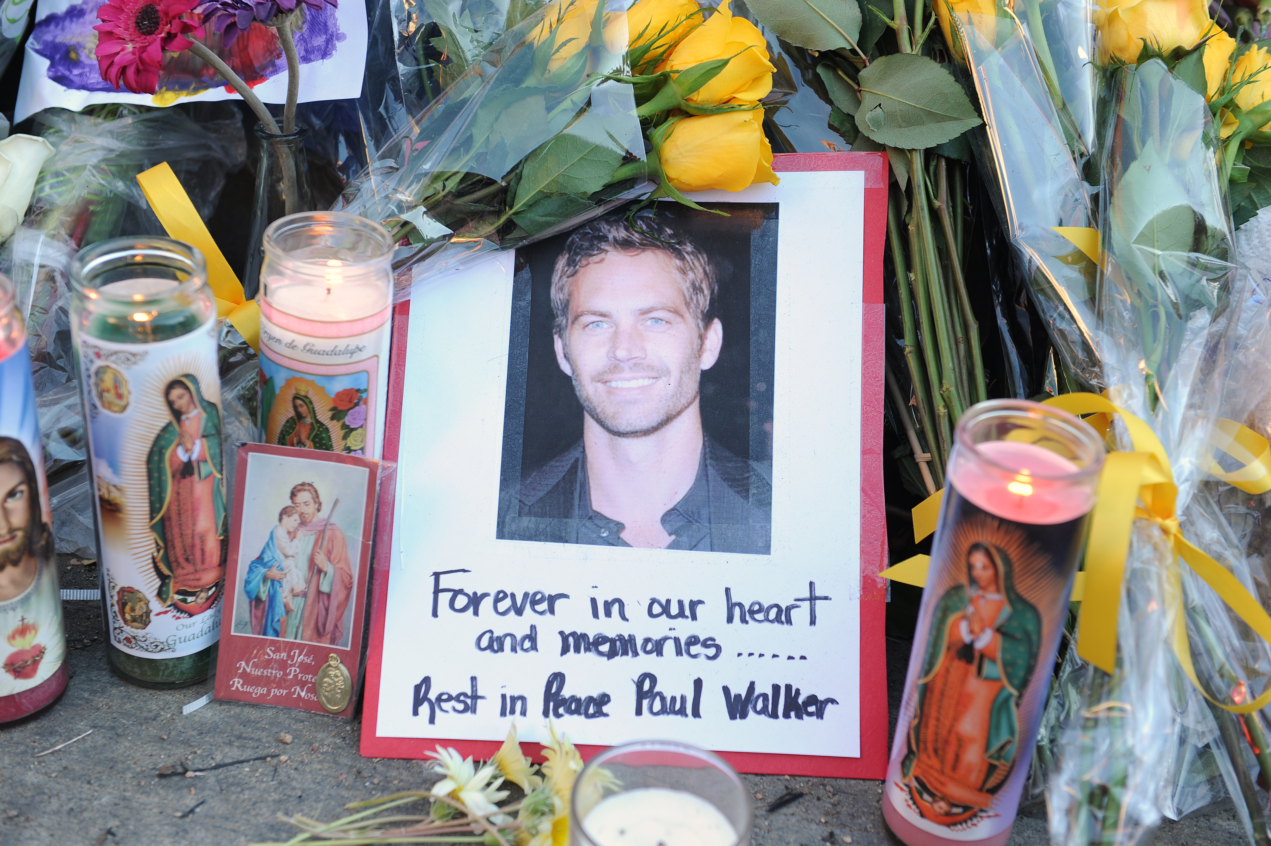 Photo de Paul Walker entourée de fleurs et de bougies à l'endroit de son accident en Californie en 2013 | Source : Getty Images