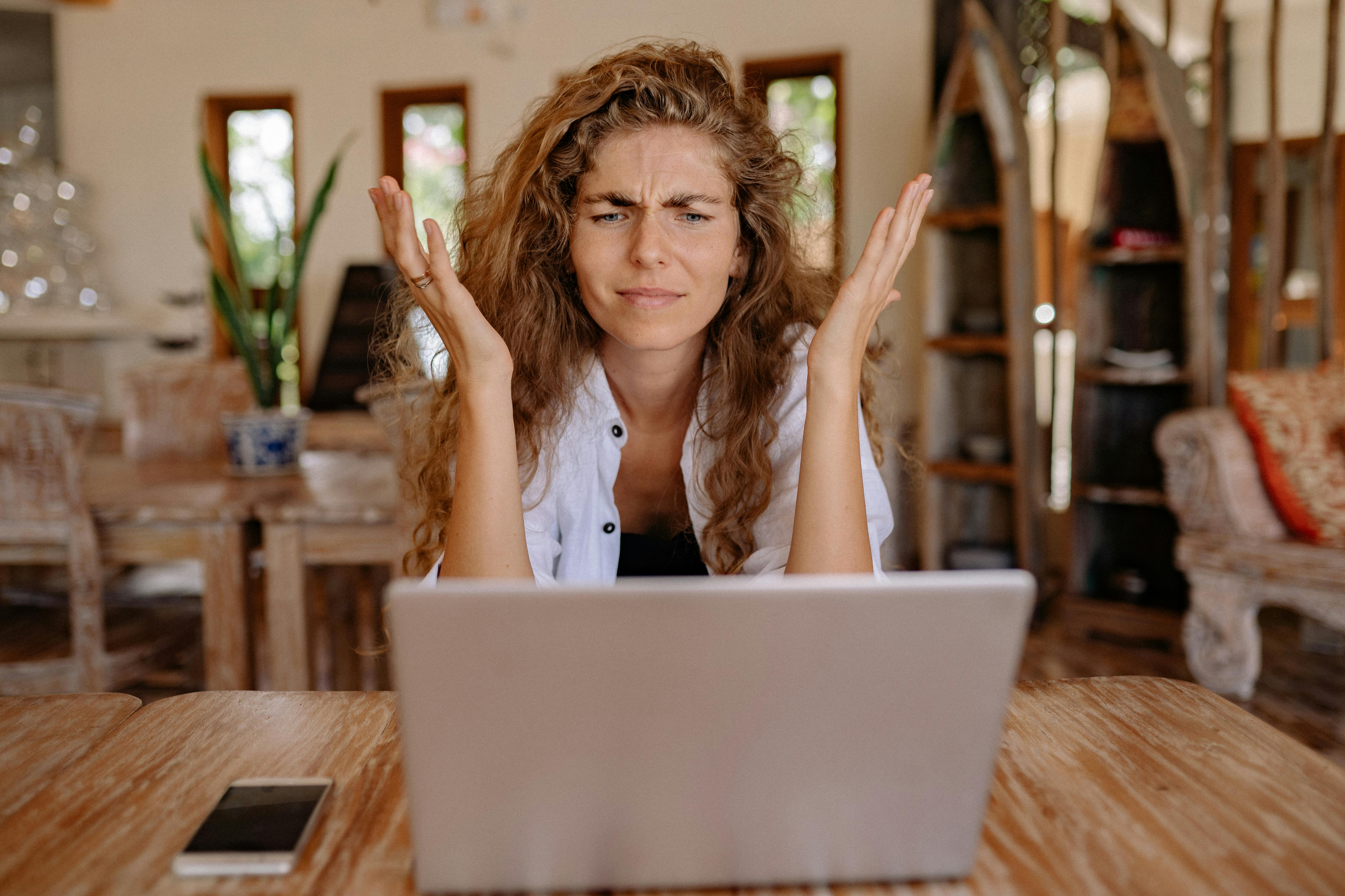 Une femme frustrée avec les mains en l'air tout en regardant l'écran d'un ordinateur portable | Source : Pexels