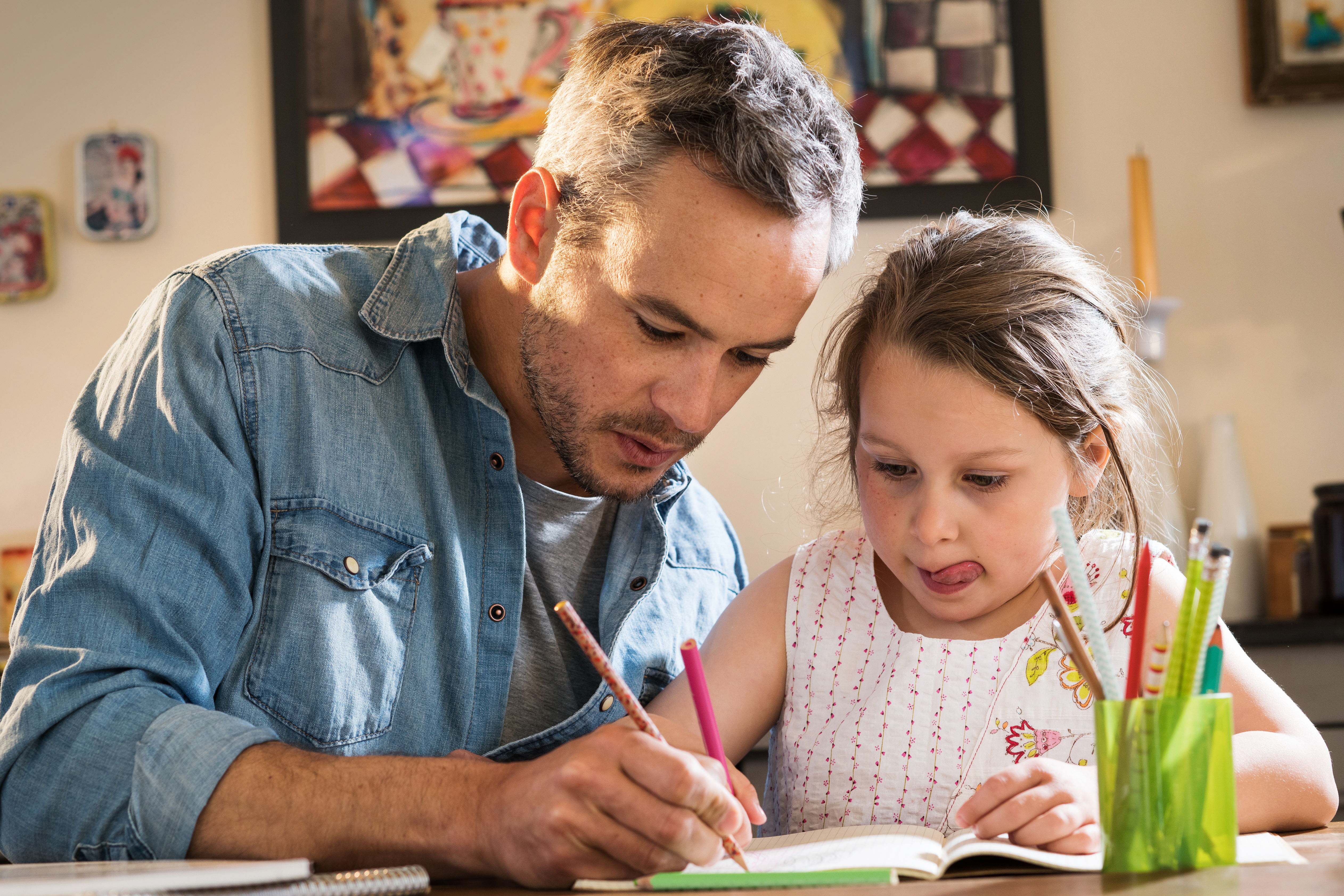 Un homme aidant un enfant à faire ses devoirs | Source : Shutterstock