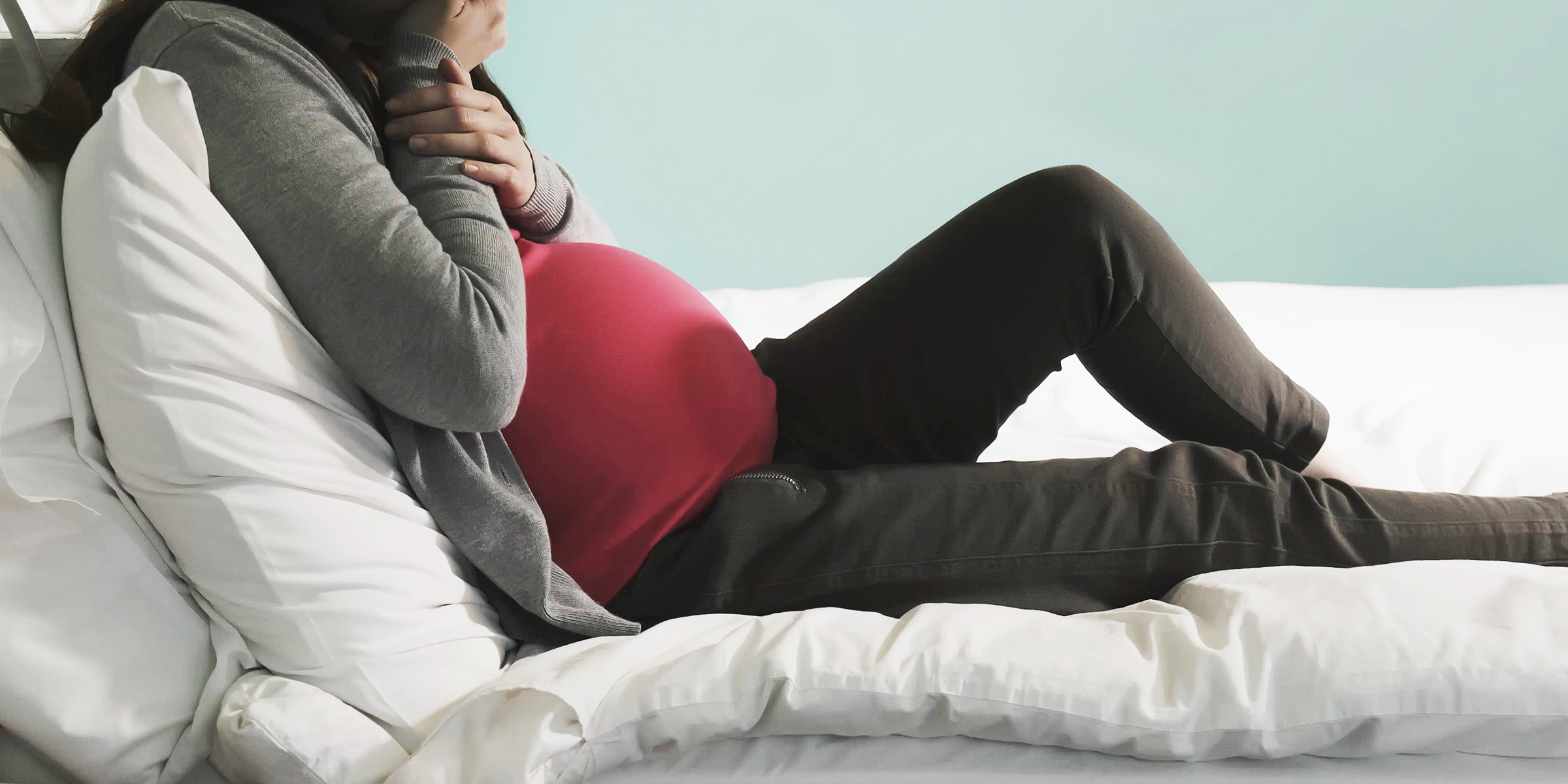 Femme enceinte assise sur un lit | Source : Shutterstock