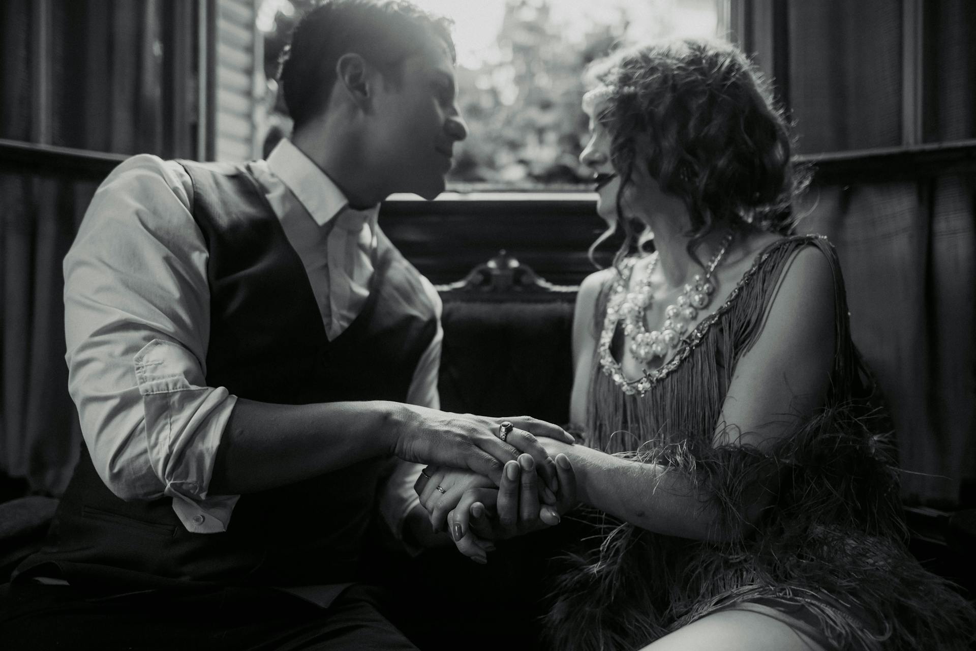 Photo en niveaux de gris d'un homme tenant les mains d'une femme riche et la regardant | Source : Pexels