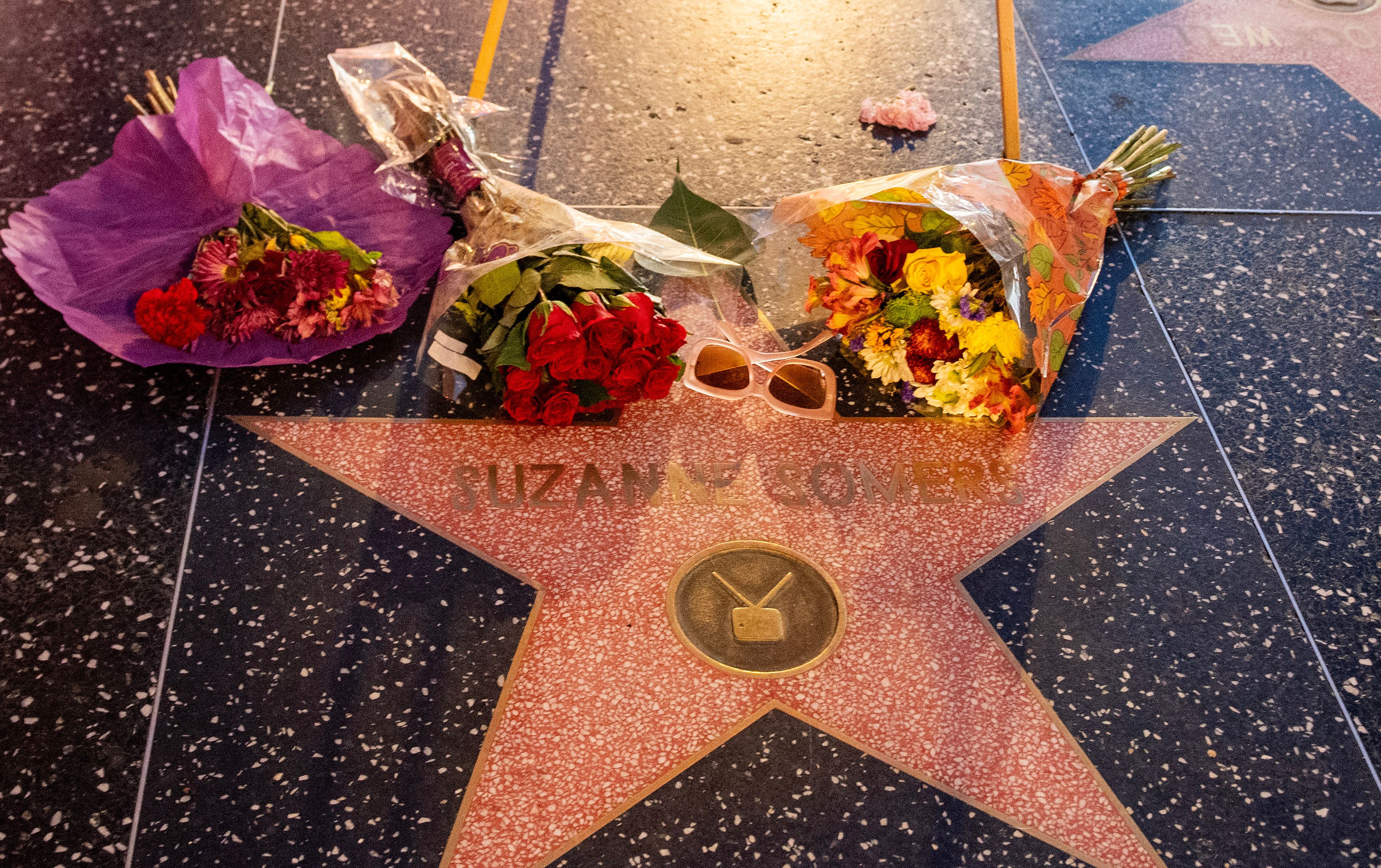 Bouquets de fleurs et paire de lunettes de soleil déposés sur l'étoile du Hollywood Walk of Fame placée en mémoire de Suzanne Somers à Hollywood, en Californie, le 16 octobre 2023 | Source : Getty Images