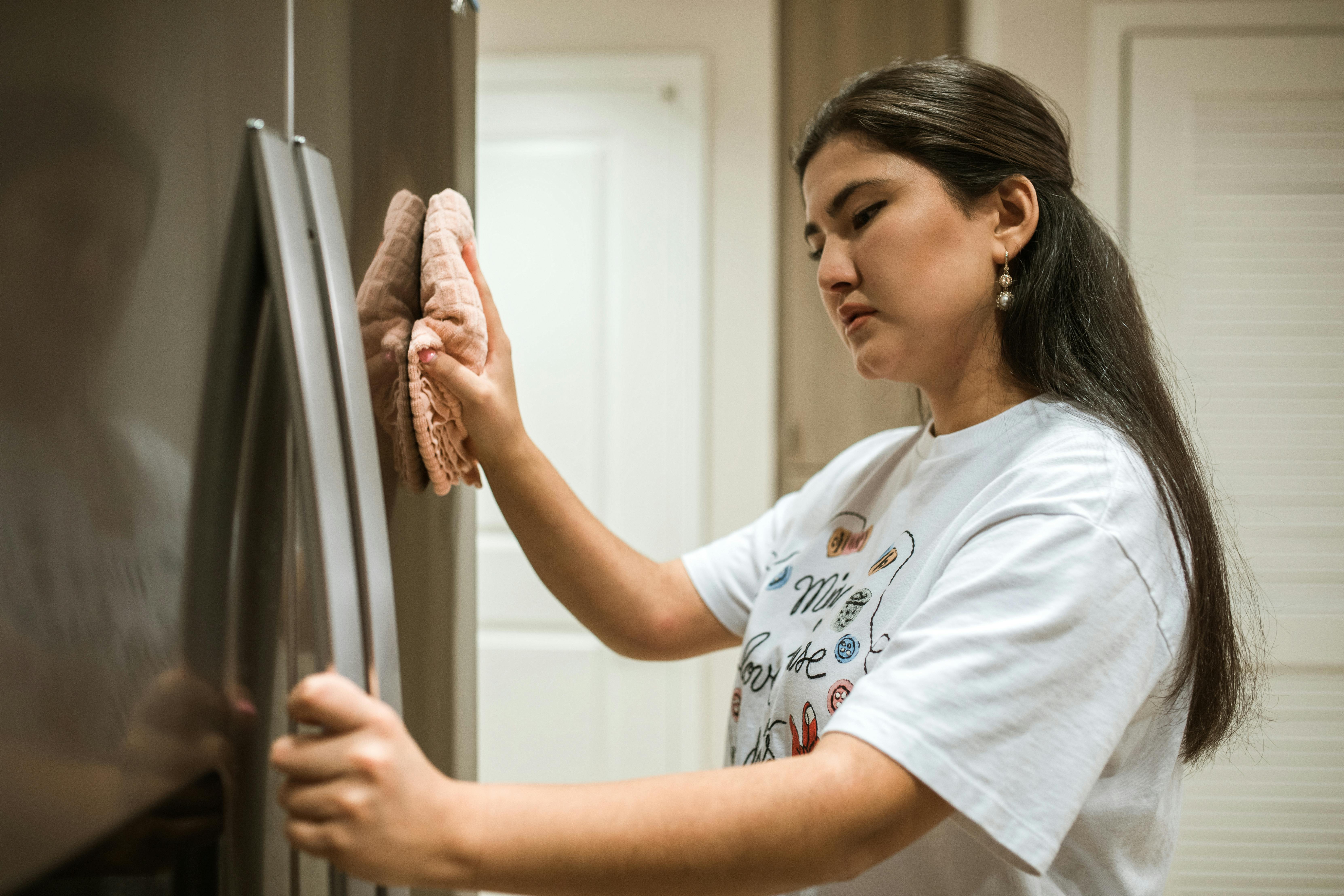 Una mujer limpiando un frigorífico. | Fuente: Pexels