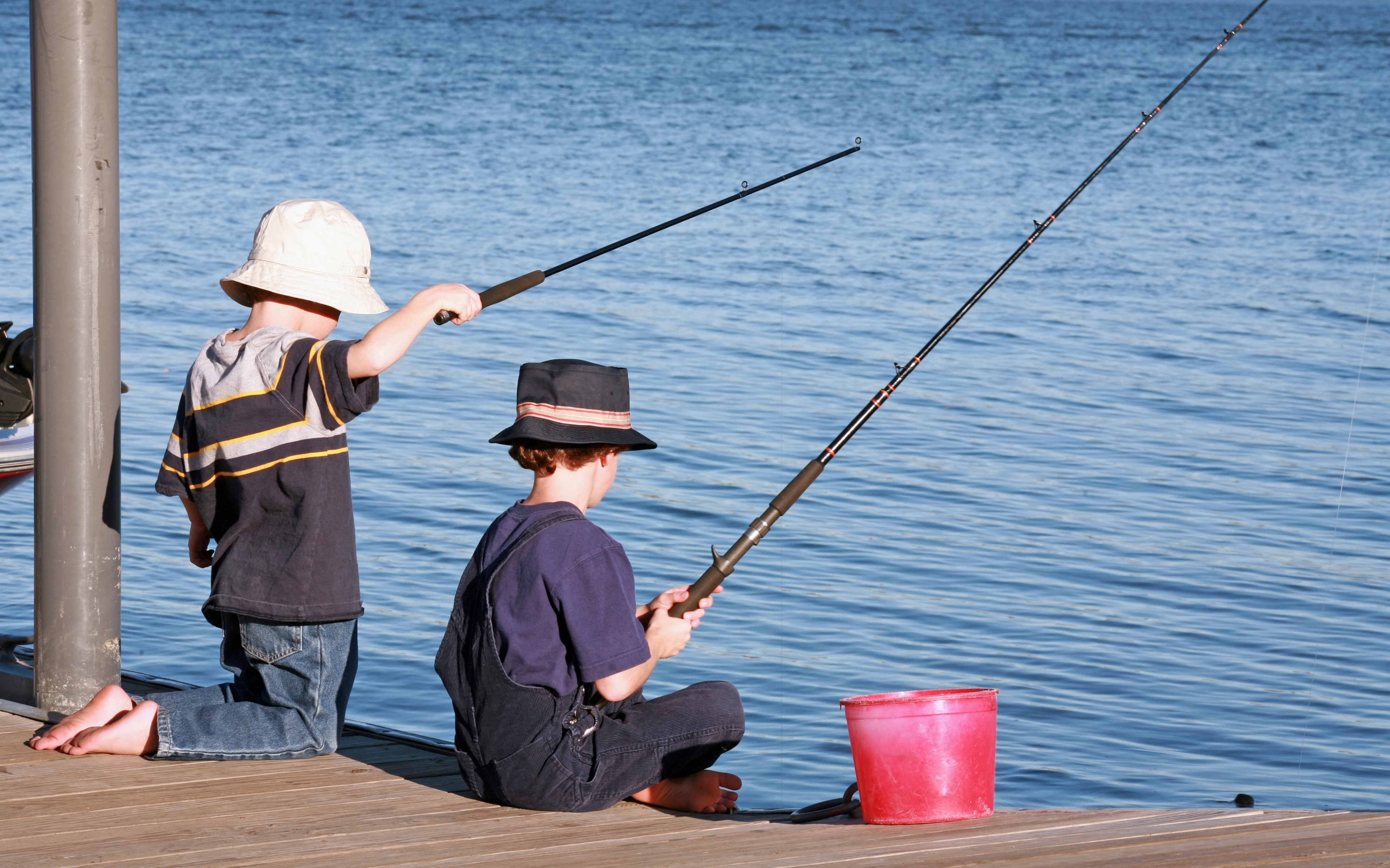 Deux jeunes garçons en train de pêcher au large d'une jetée | Source : Shutterstock