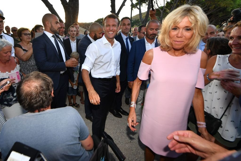 Le président français Emmanuel Macron et son épouse Brigitte Macron sont salués par des sympathisants après avoir marqué le 74e anniversaire de la libération de Bormes-les-Mimosas pendant la Seconde Guerre mondiale, le 17 août 2018. | Photo : Getty Images