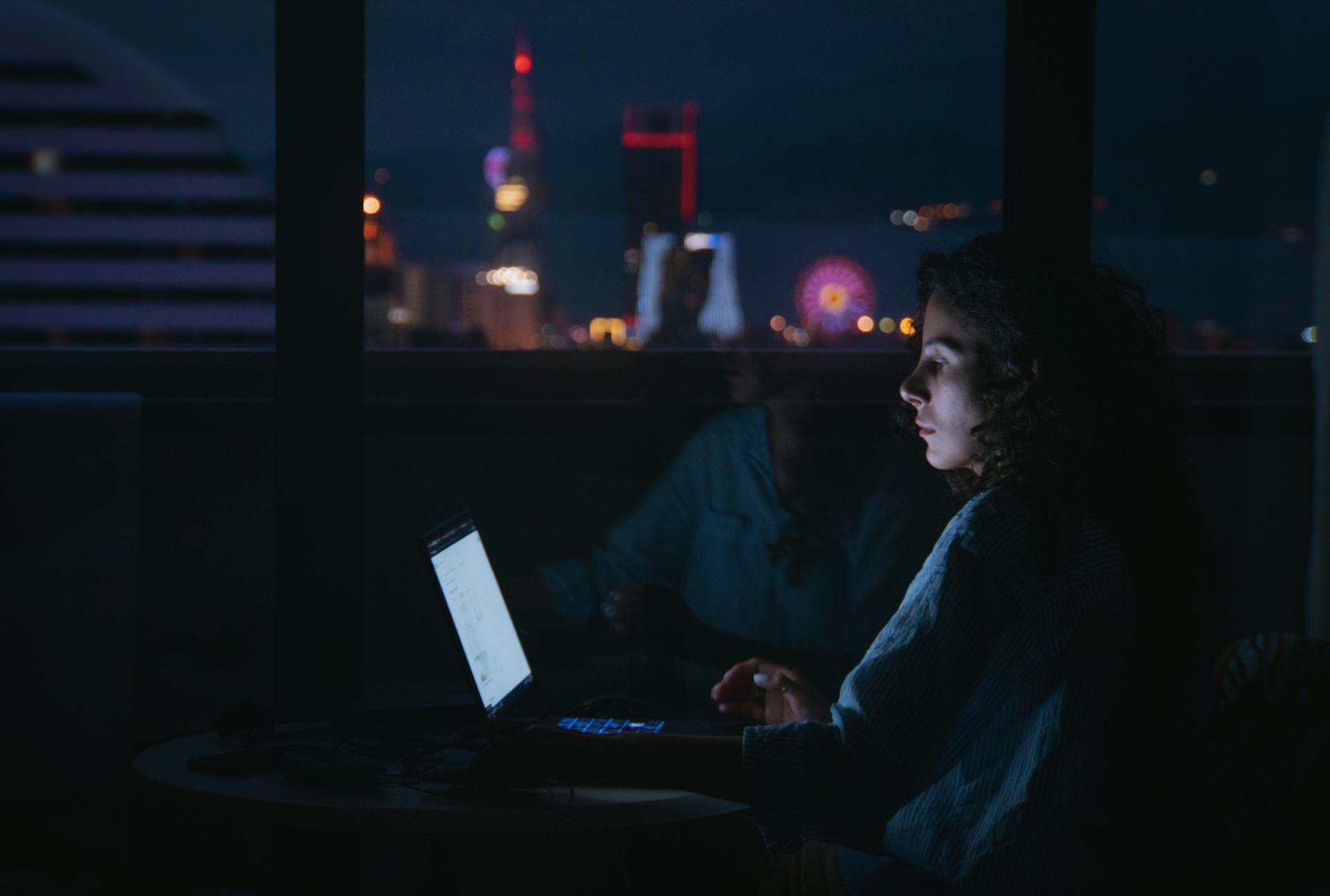Une femme utilisant son ordinateur portable dans l'obscurité | Source : Pexels