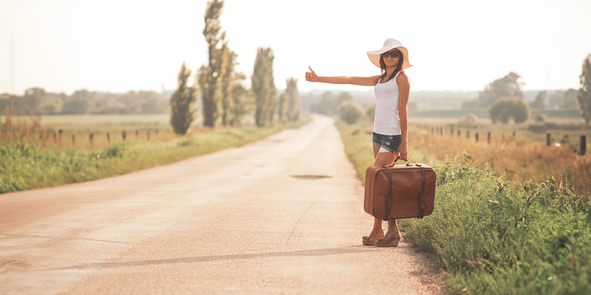 Une jeune femme avec une valise sur une route | Source : Shutterstock