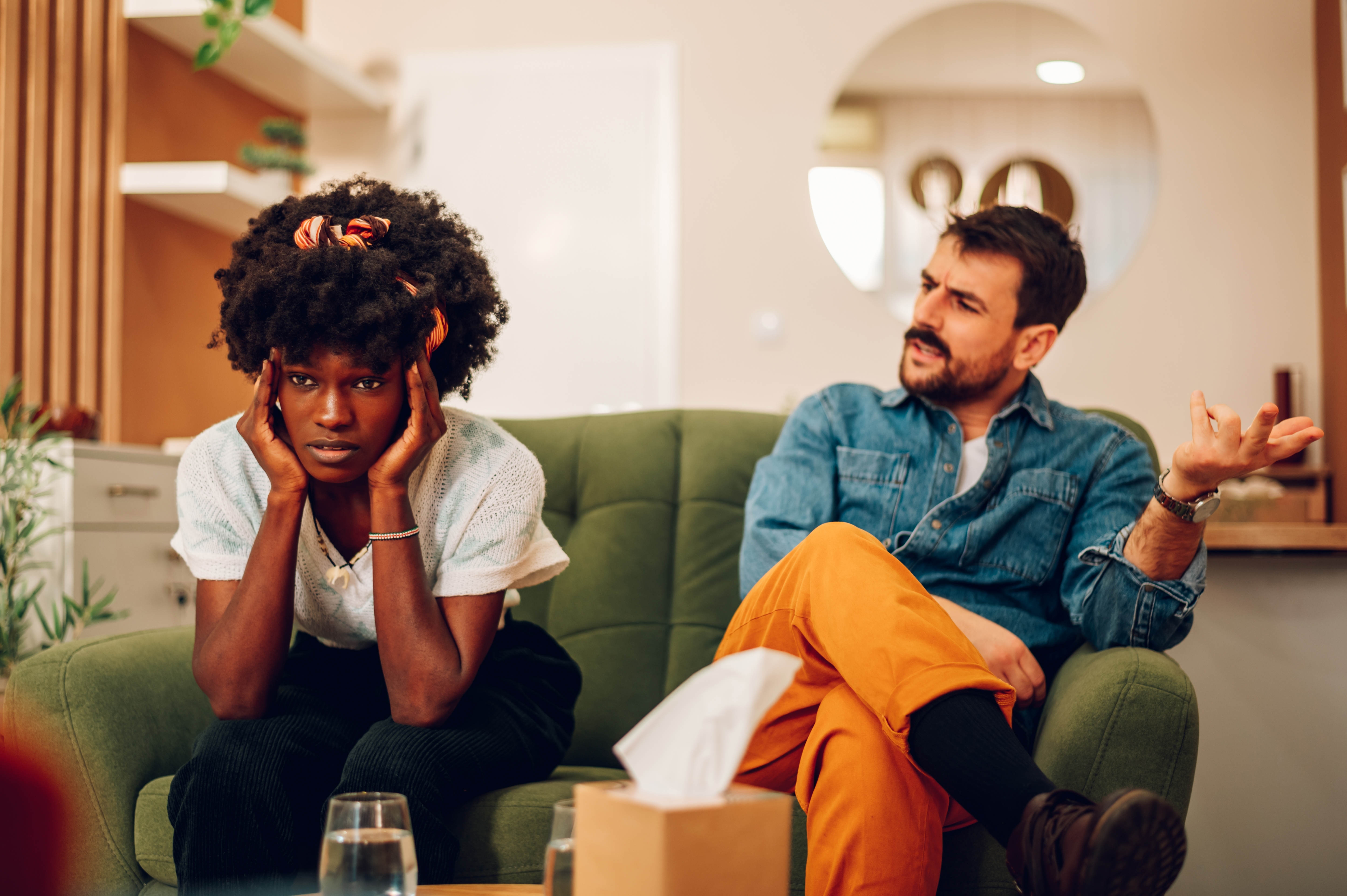 Un homme blanc et une femme noire en désaccord, assis sur un canapé. | Source : Shutterstock