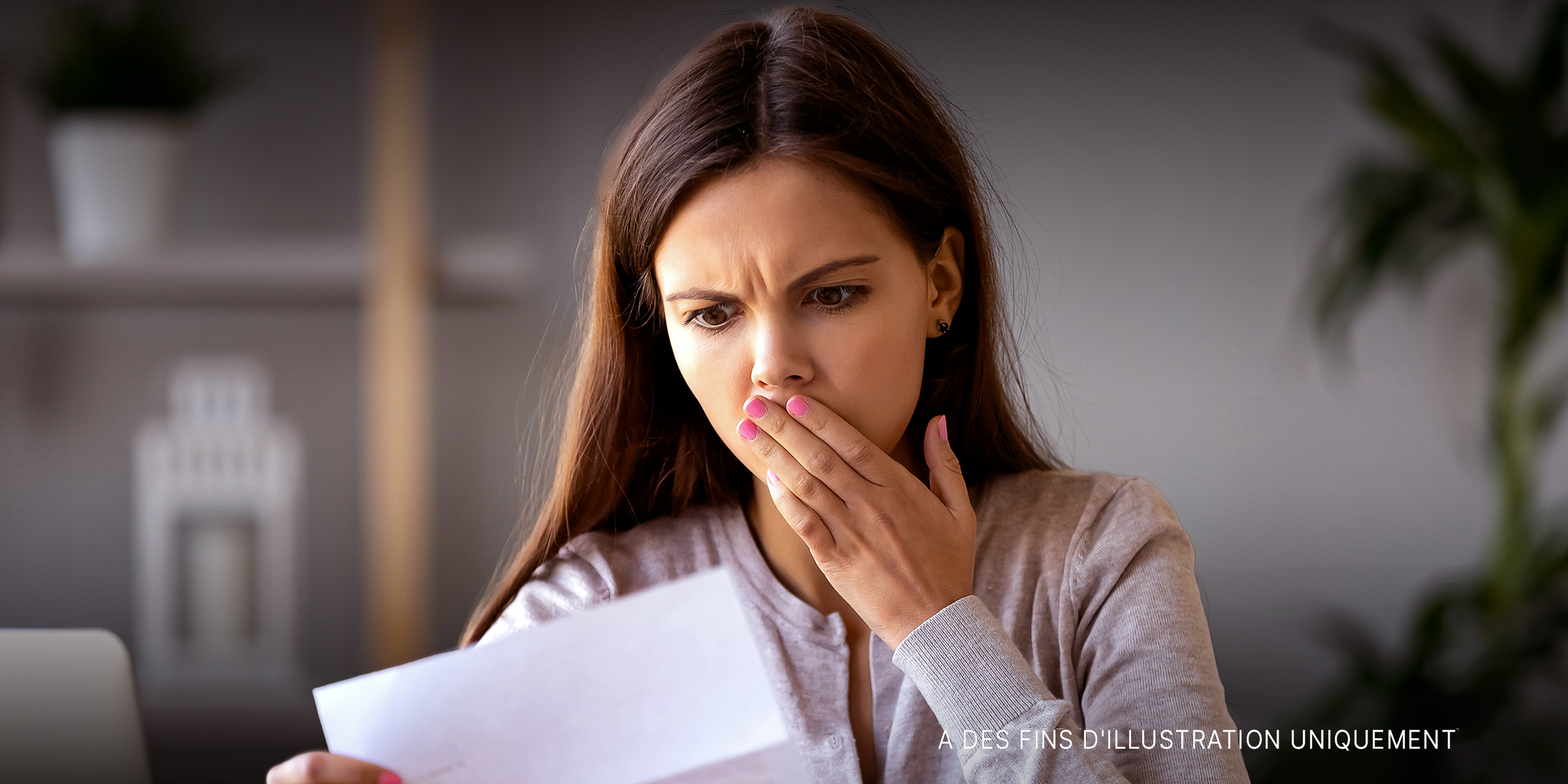Une femme choquée qui regarde une lettre | Source : Shutterstock