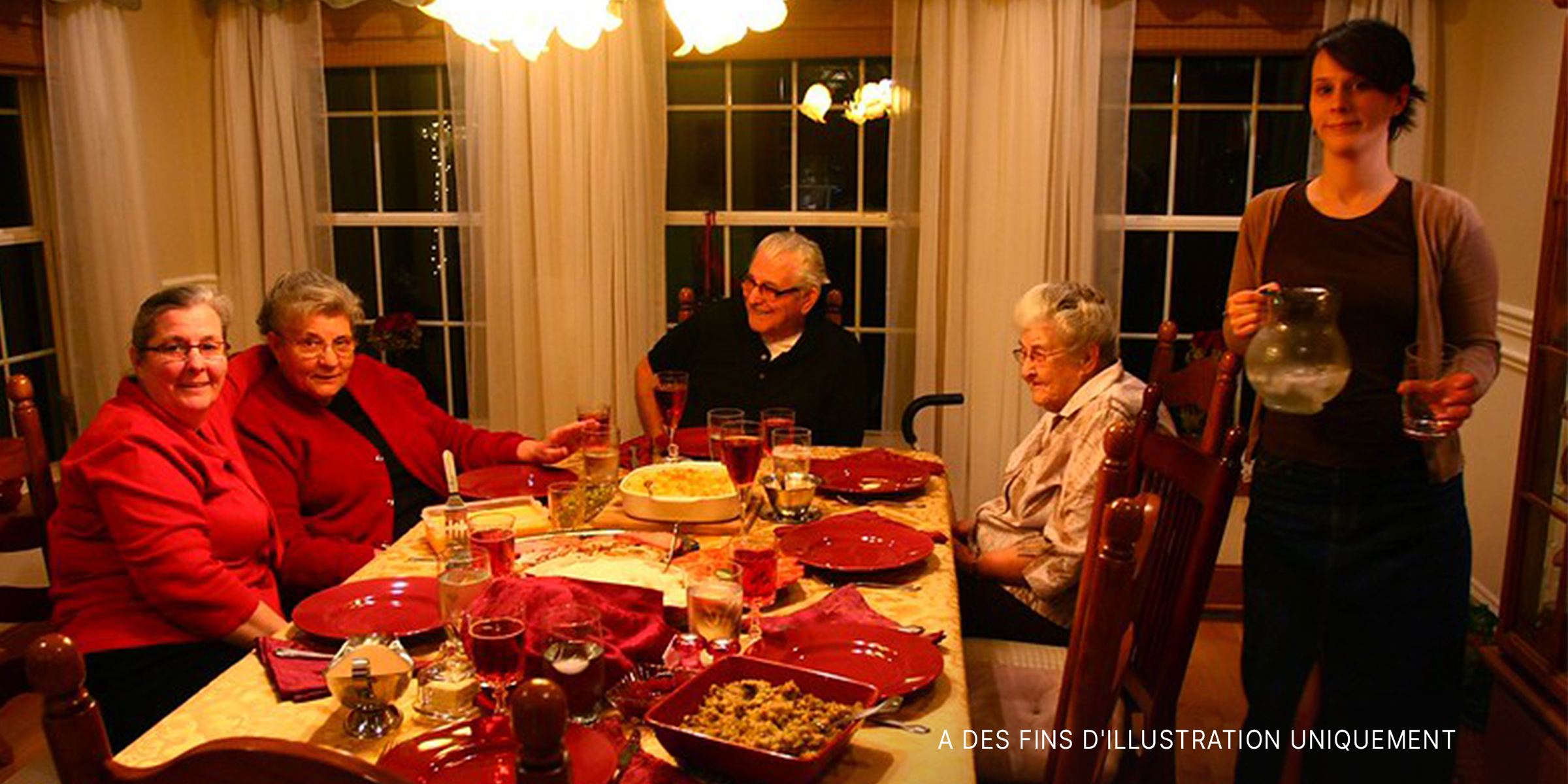Une femme serveur se tient près d'une famille réunie pour le repas de Noël | Source : Flickr.com/Martin Cathrae/CC BY-SA 2.0