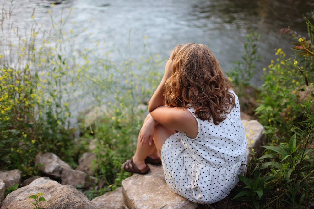 Femme assise au bord du lac | Photo: Pexels