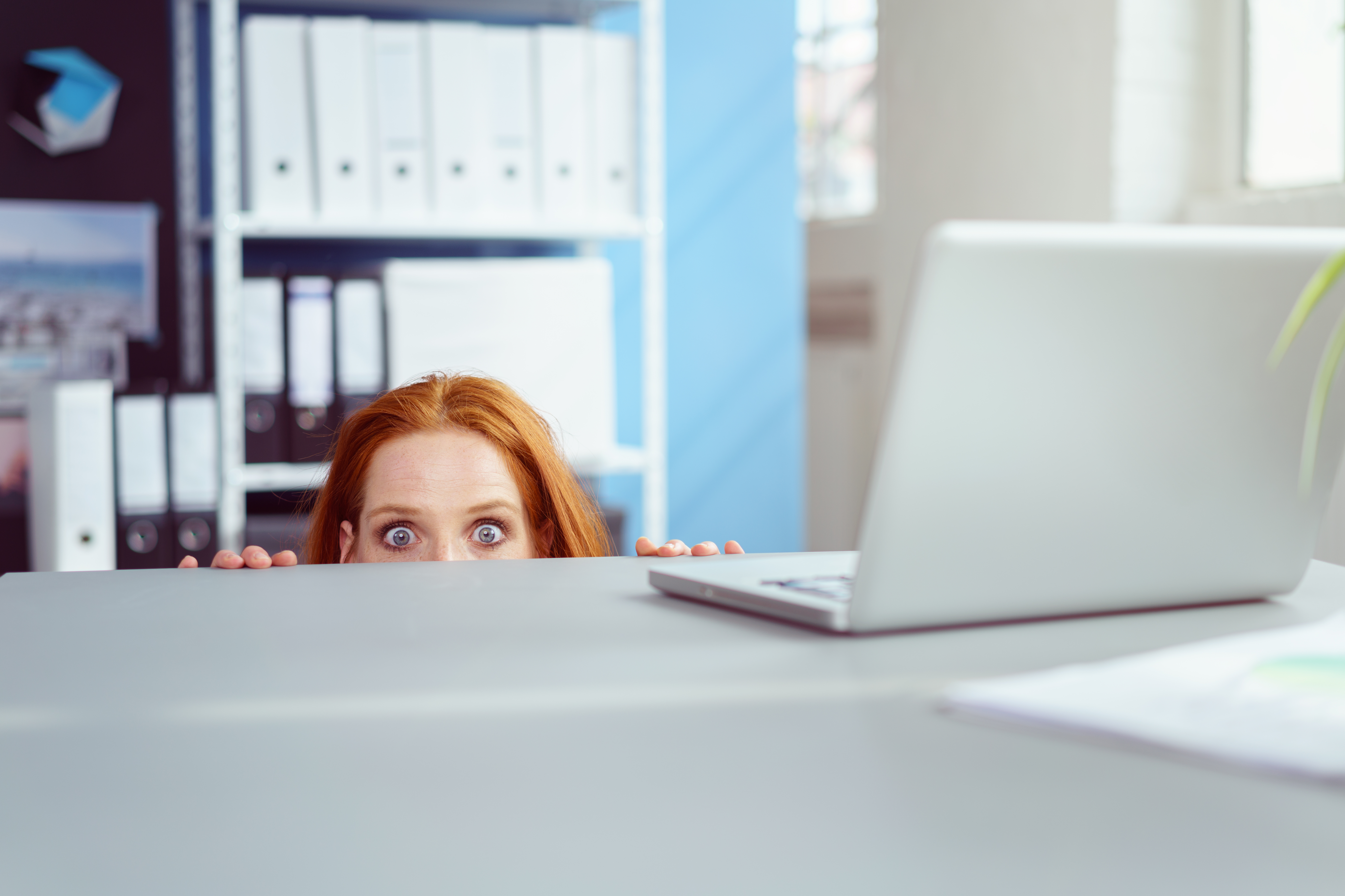 Une femme se cachant sous un bureau | Source : Shutterstock