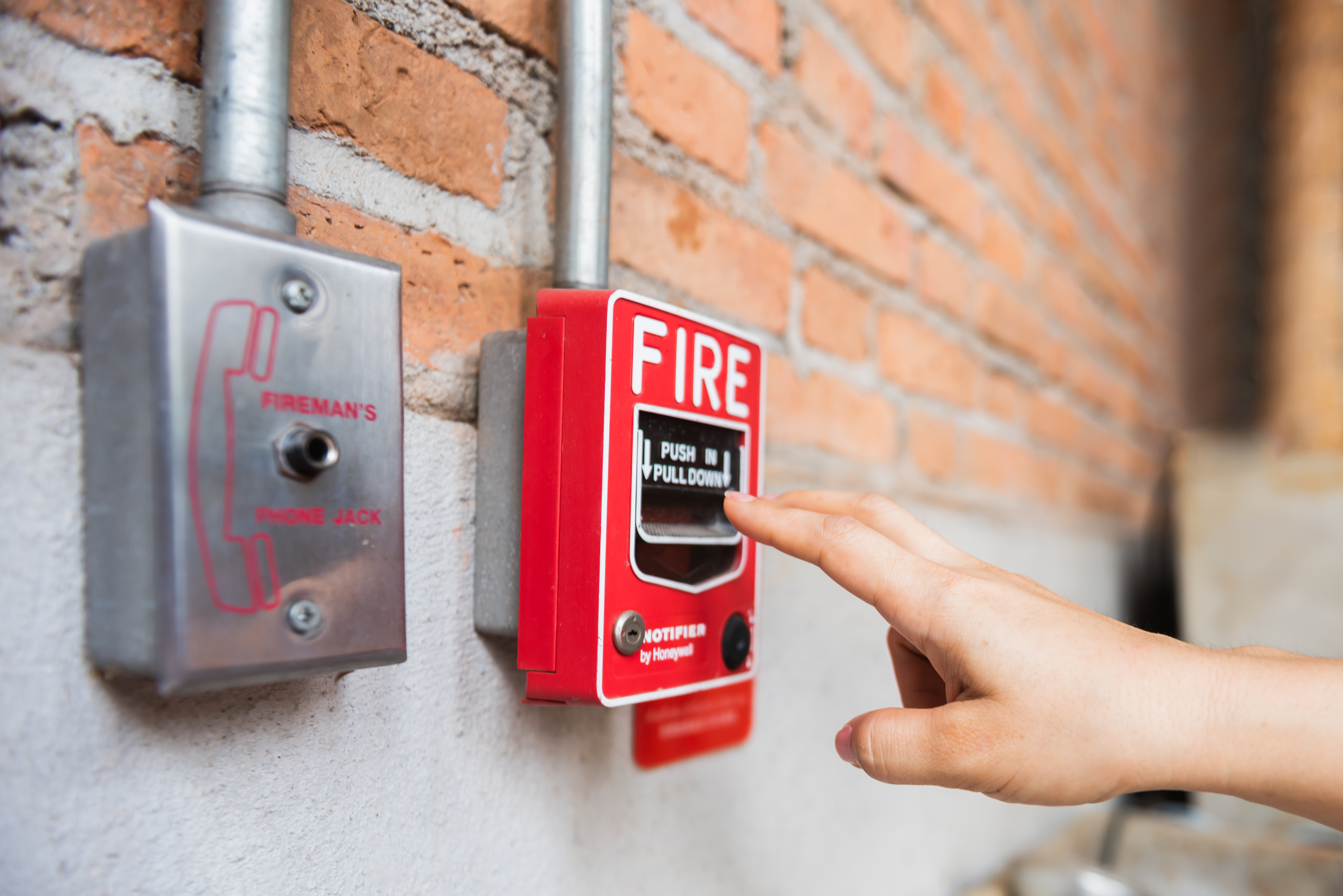 Main d'une femme tendant la main vers le système d'interrupteur d'alarme incendie | Source : Getty Images