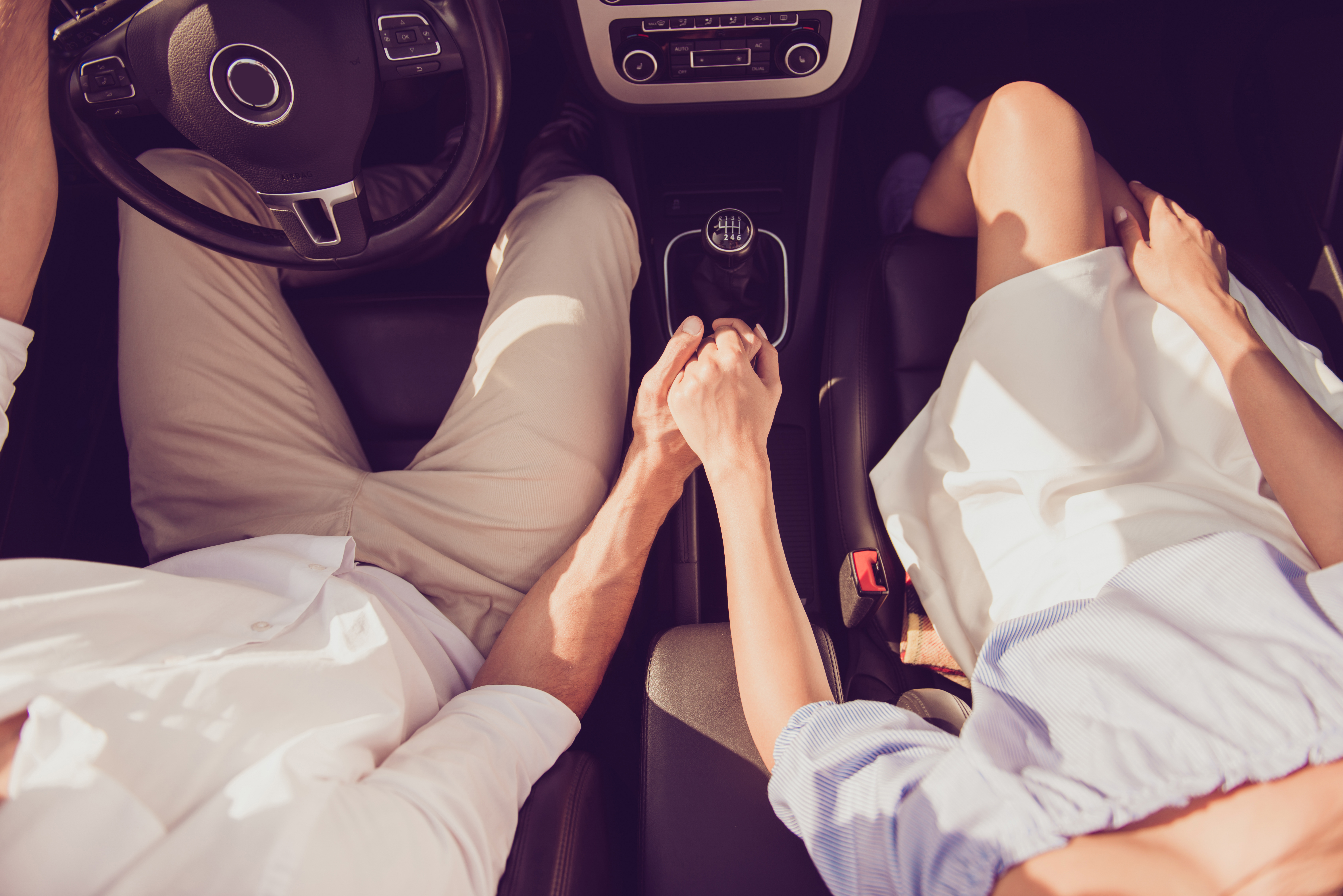 Un couple se tenant par la main dans une voiture | Source : Shutterstock