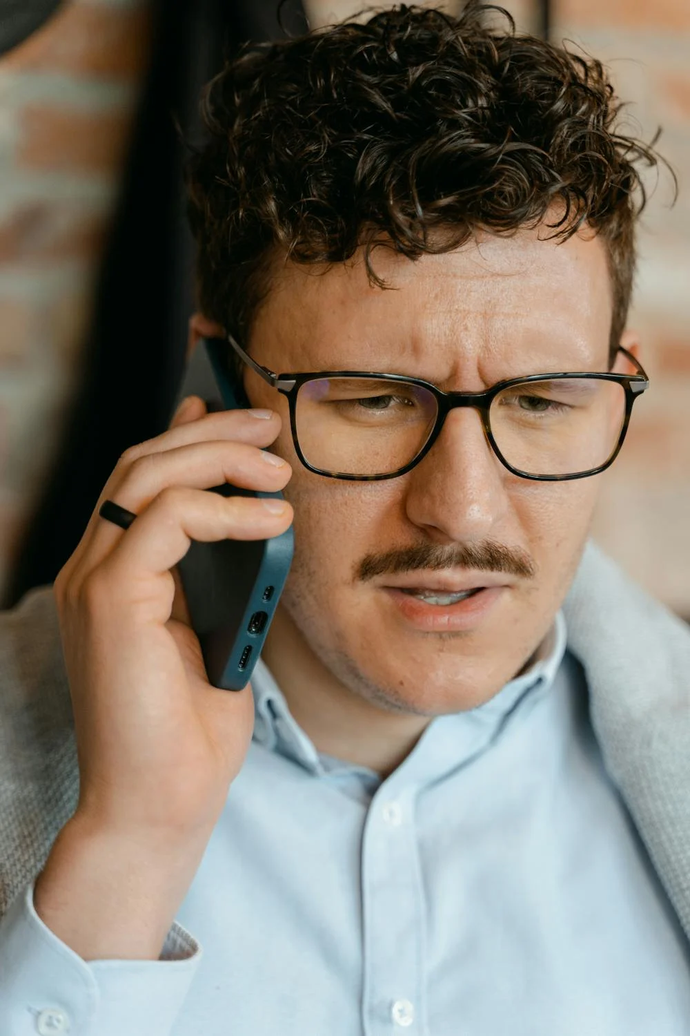 Un homme qui fronce les sourcils en parlant au téléphone | Source : Pexels