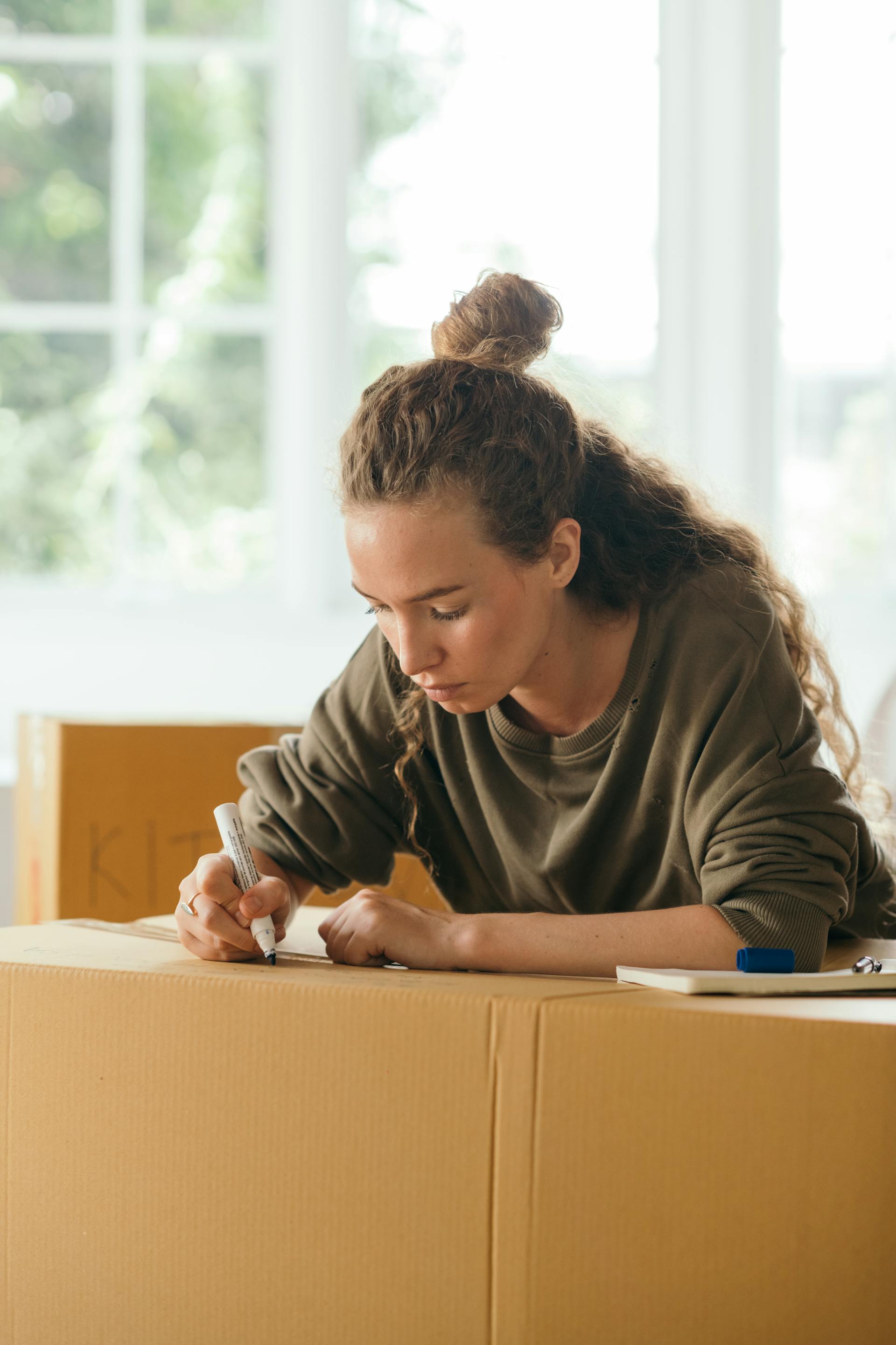 Une femme qui écrit sur un carton de déménagement | Source : Pexels