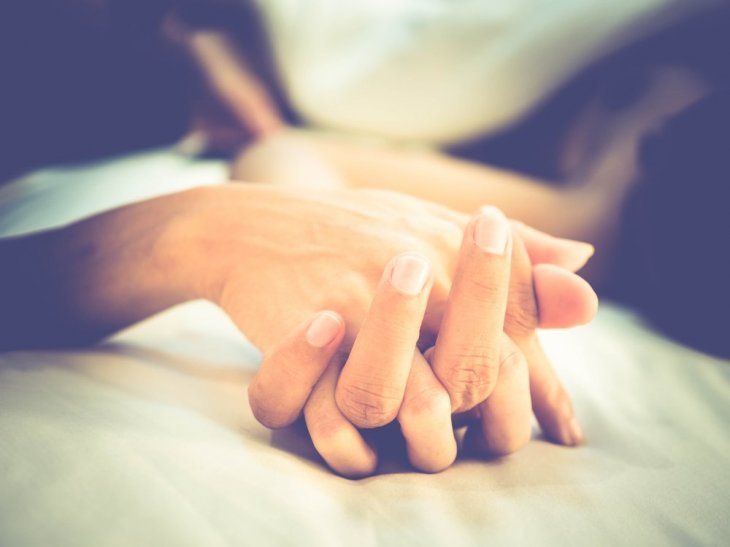 Un couple se tenant la main dans son lit. l Source: Shutterstock