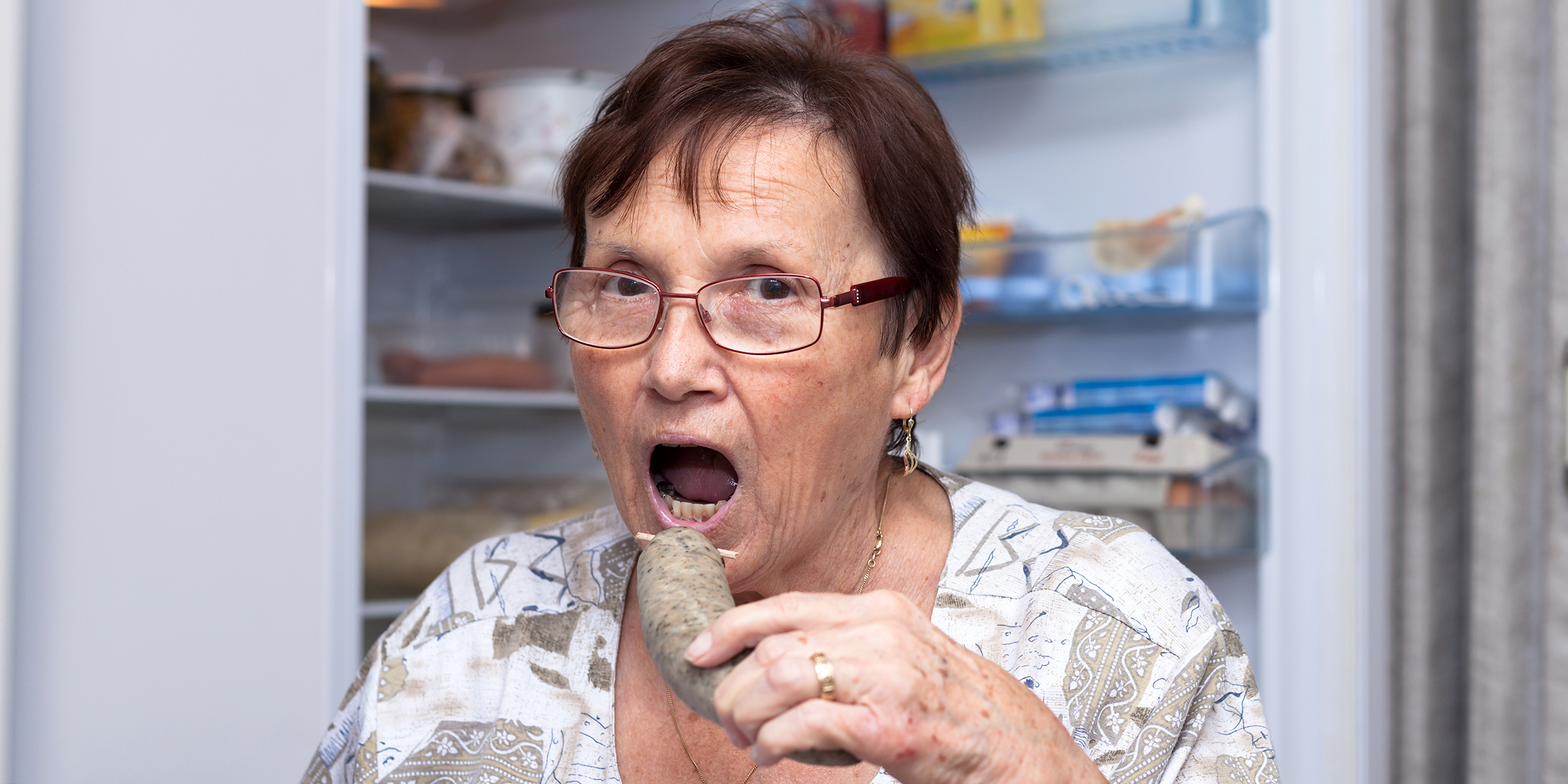 Une femme mangeant devant le réfrigérateur | Source : Shutterstock