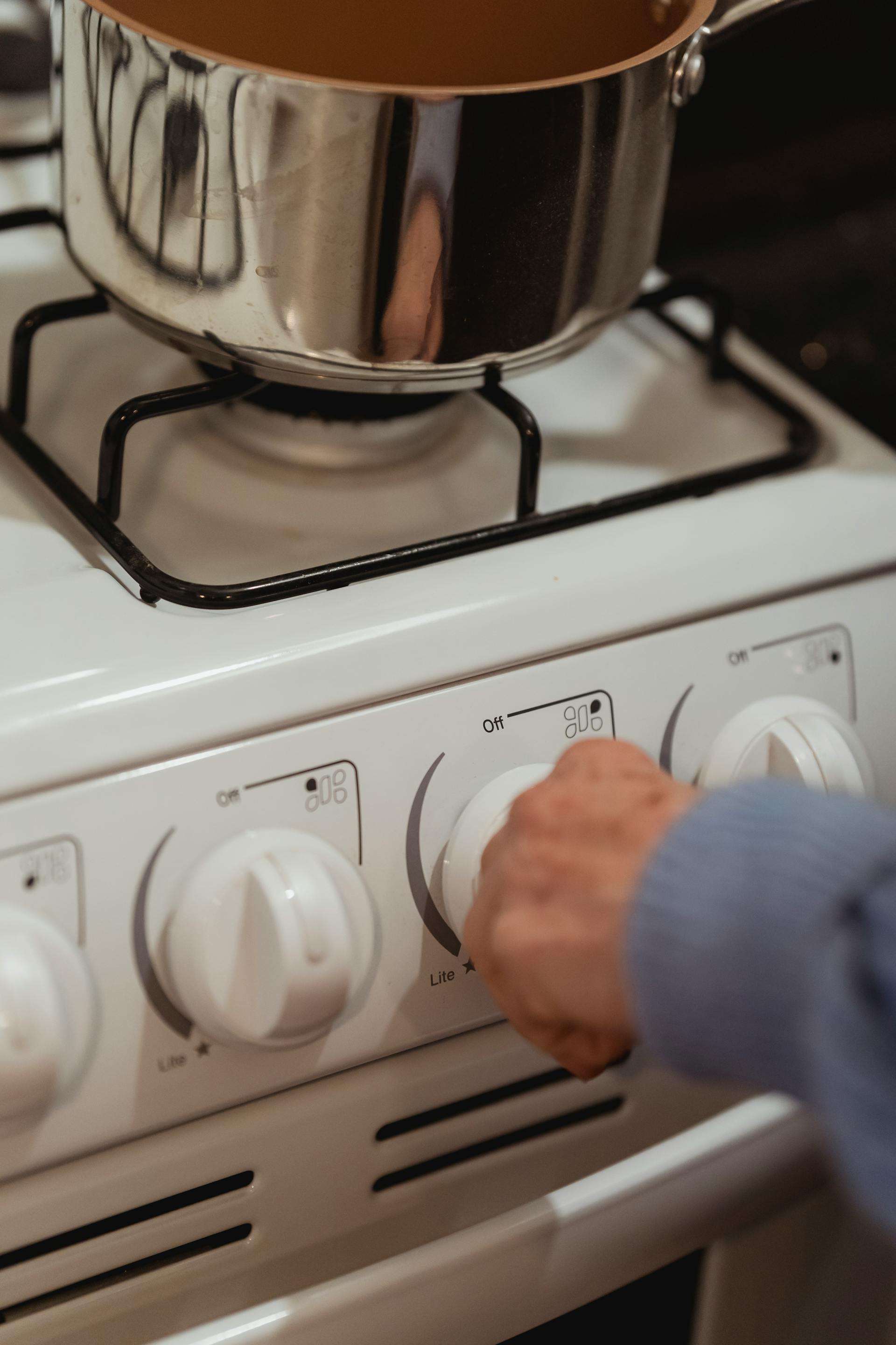 Gros plan d'une femme tournant le bouton d'une cuisinière | Source : Pexels