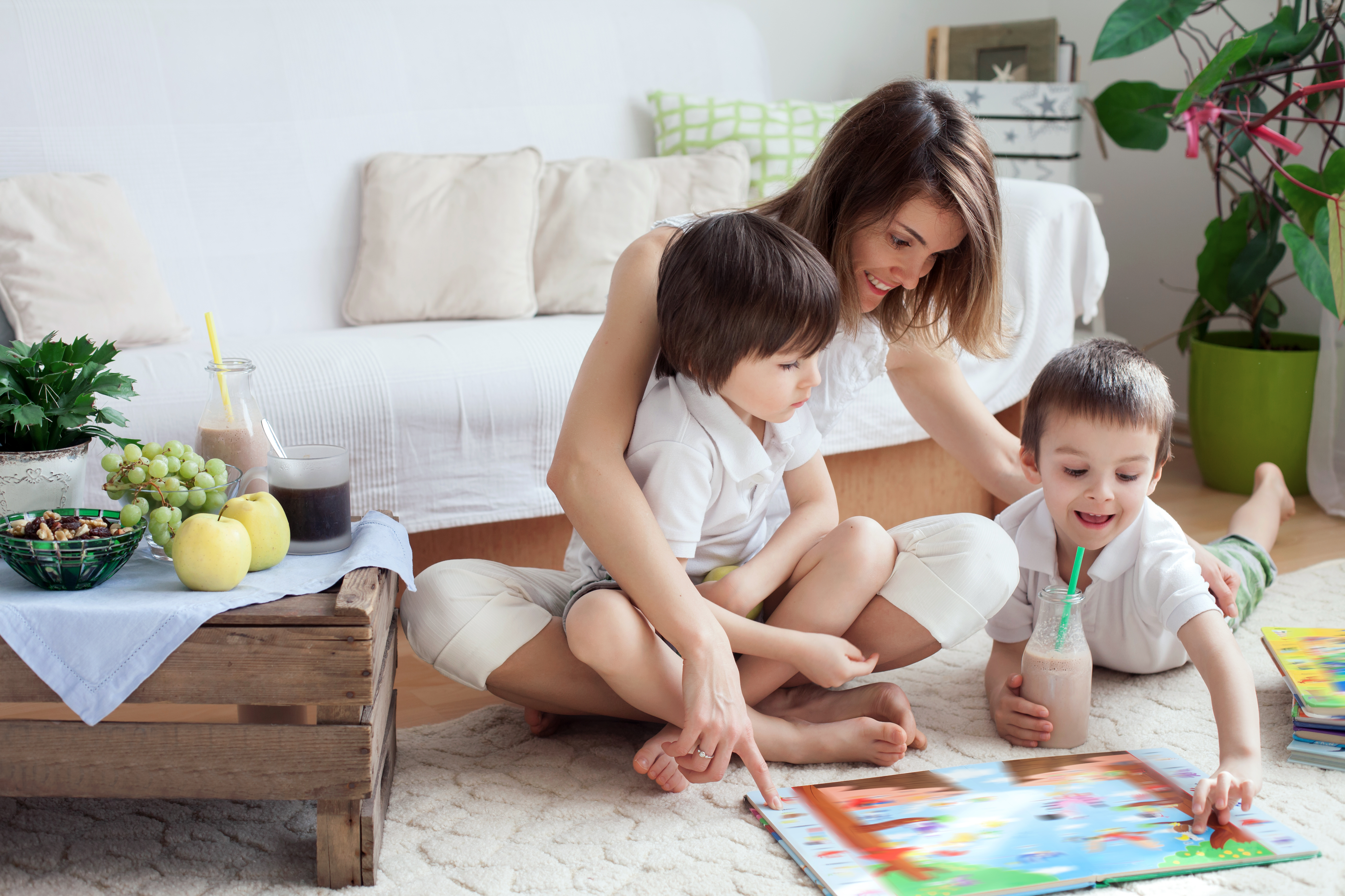 Une femme par terre lisant un livre avec ses deux enfants | Source : Shutterstock
