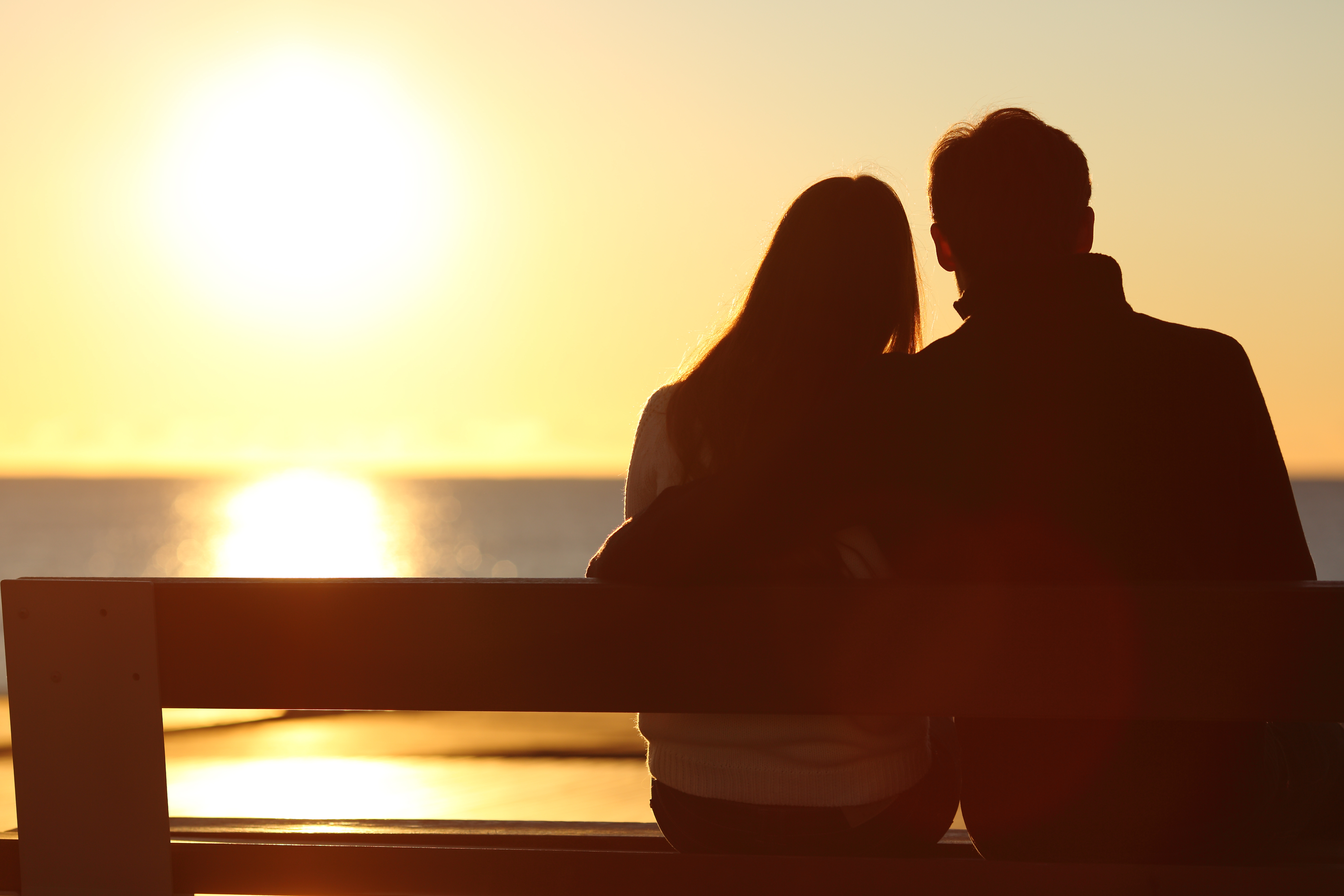 Silhouette d'un couple regardant le soleil sur la plage | Source : Shutterstock