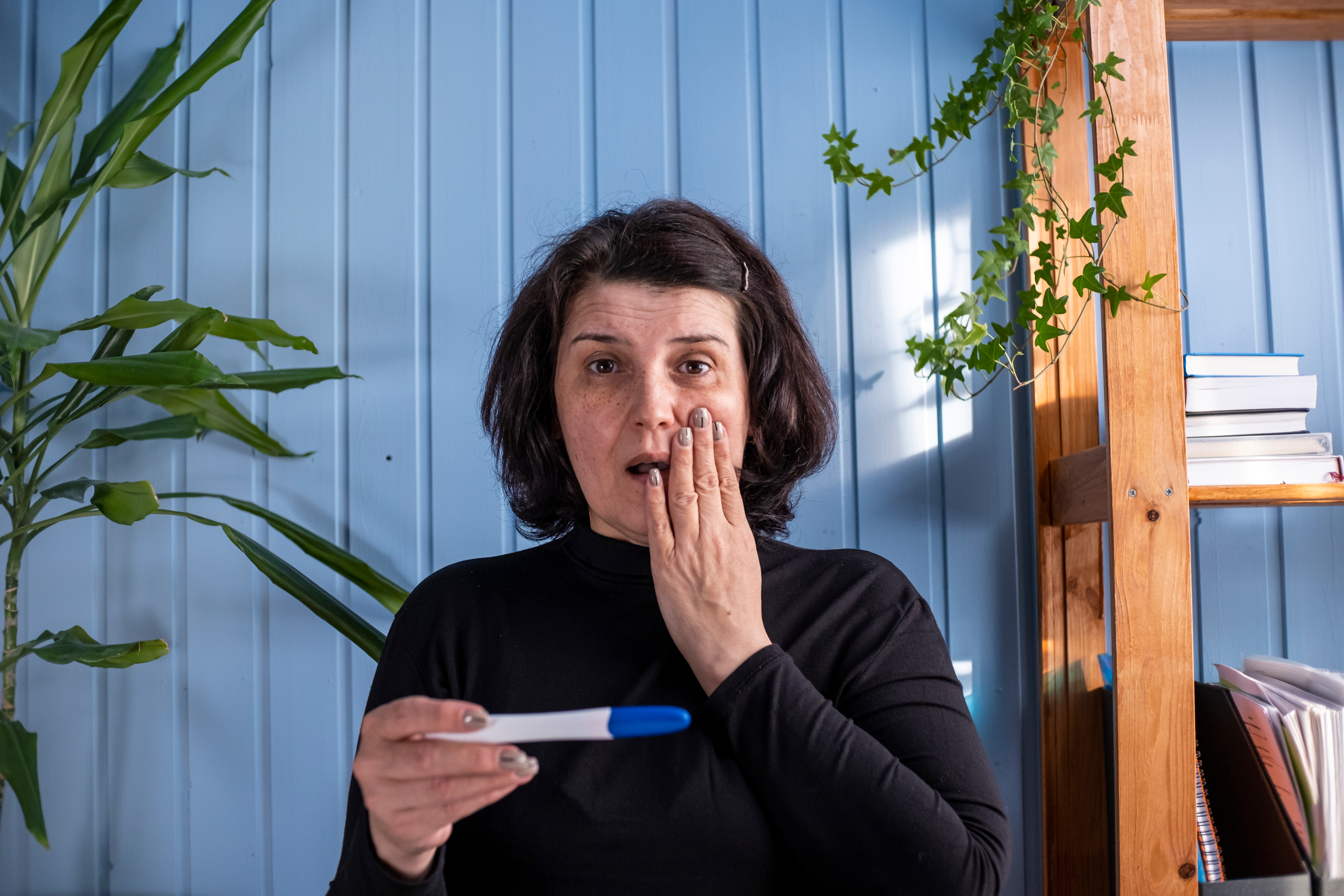 Une femme d'âge moyen regarde le résultat d'un test de grossesse qui s'avère positif : Shutterstock