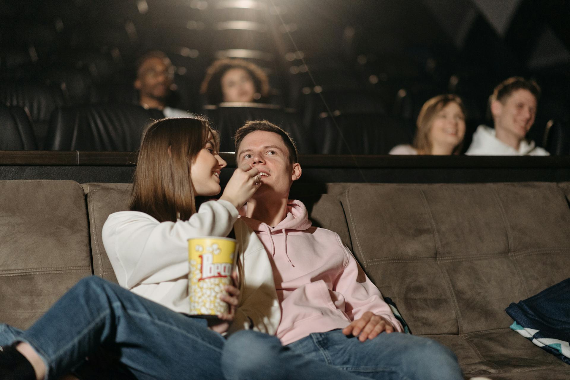 Couple mangeant du pop-corn tout en regardant un film dans un cinéma | Source : Pexels