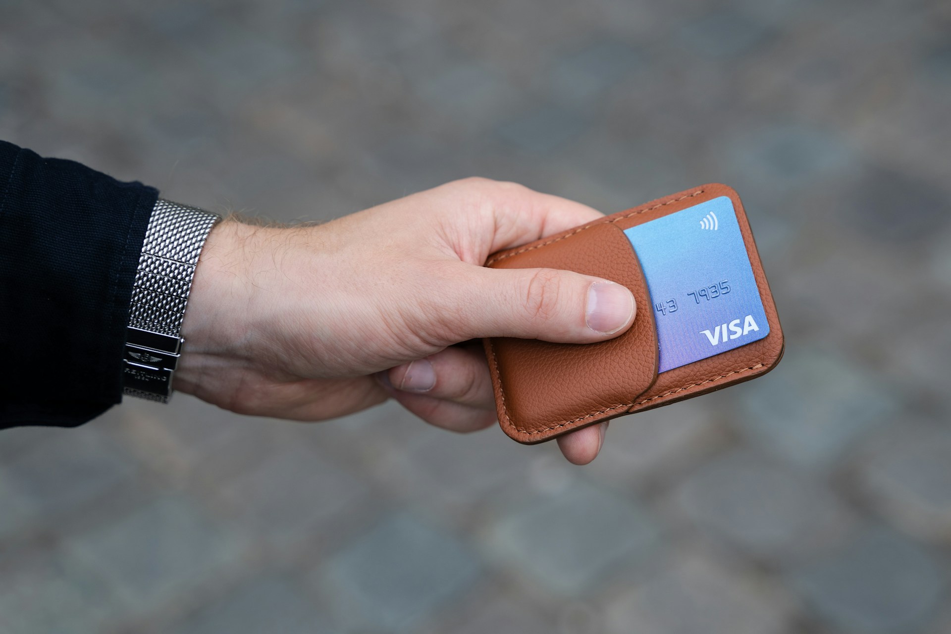 Un homme tenant une carte bancaire dans un porte-carte en cuir | Source : Unsplash
