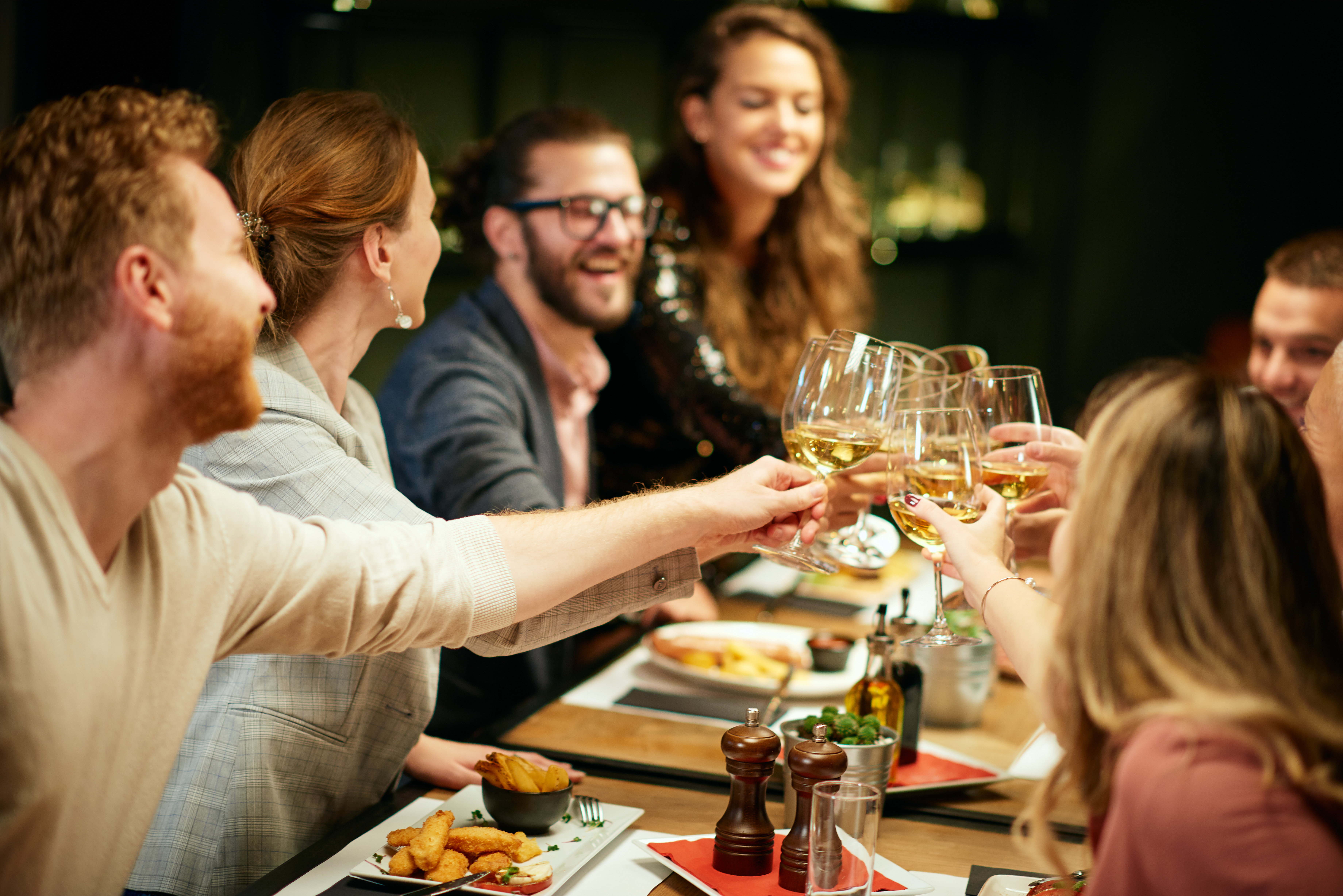 Un groupe d'amis assis dans un restaurant pour le dîner et levant leurs verres | Source : Shutterstock
