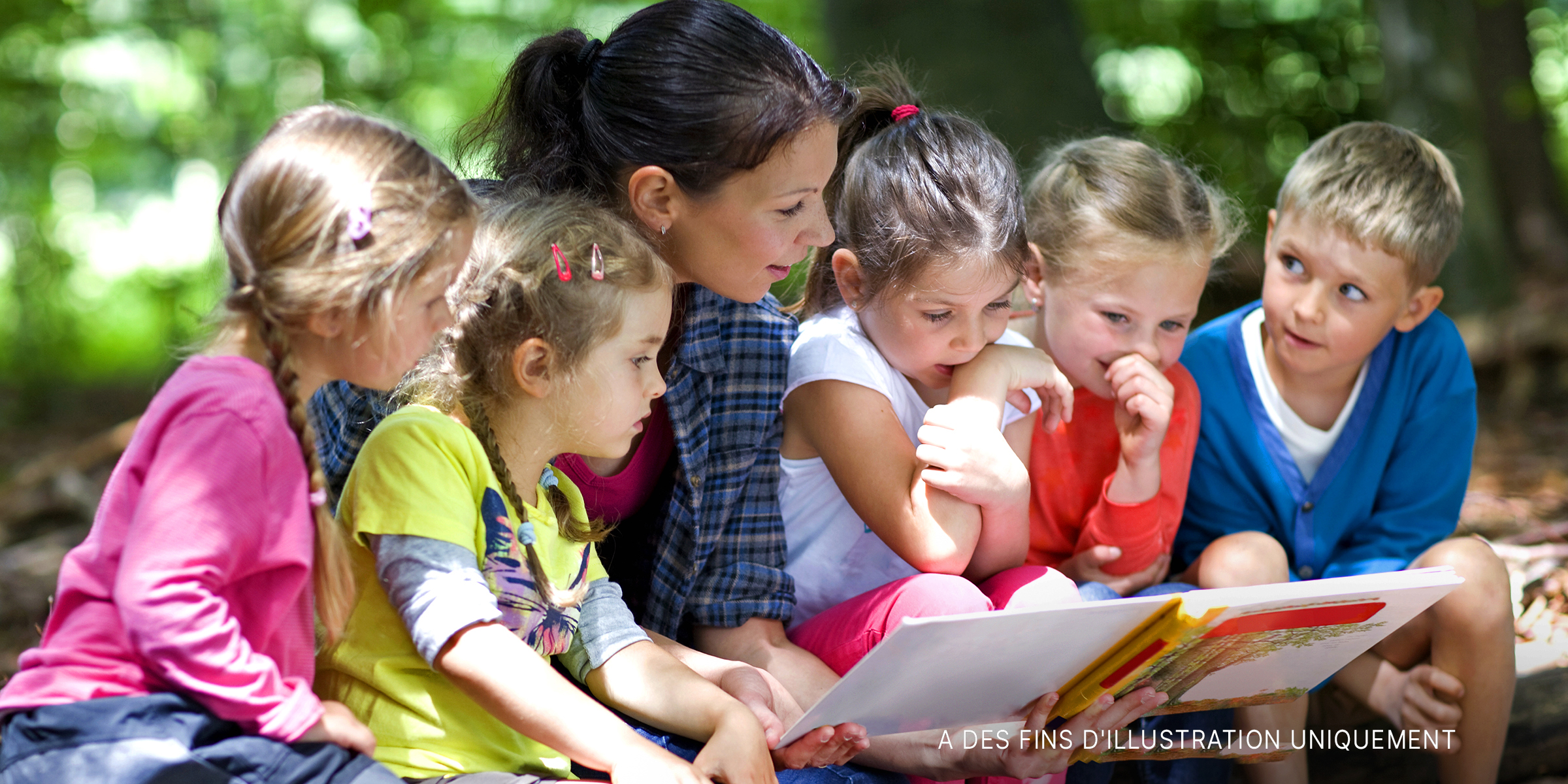 Une femme lisant un livre à de jeunes enfants | Source : Shutterstock