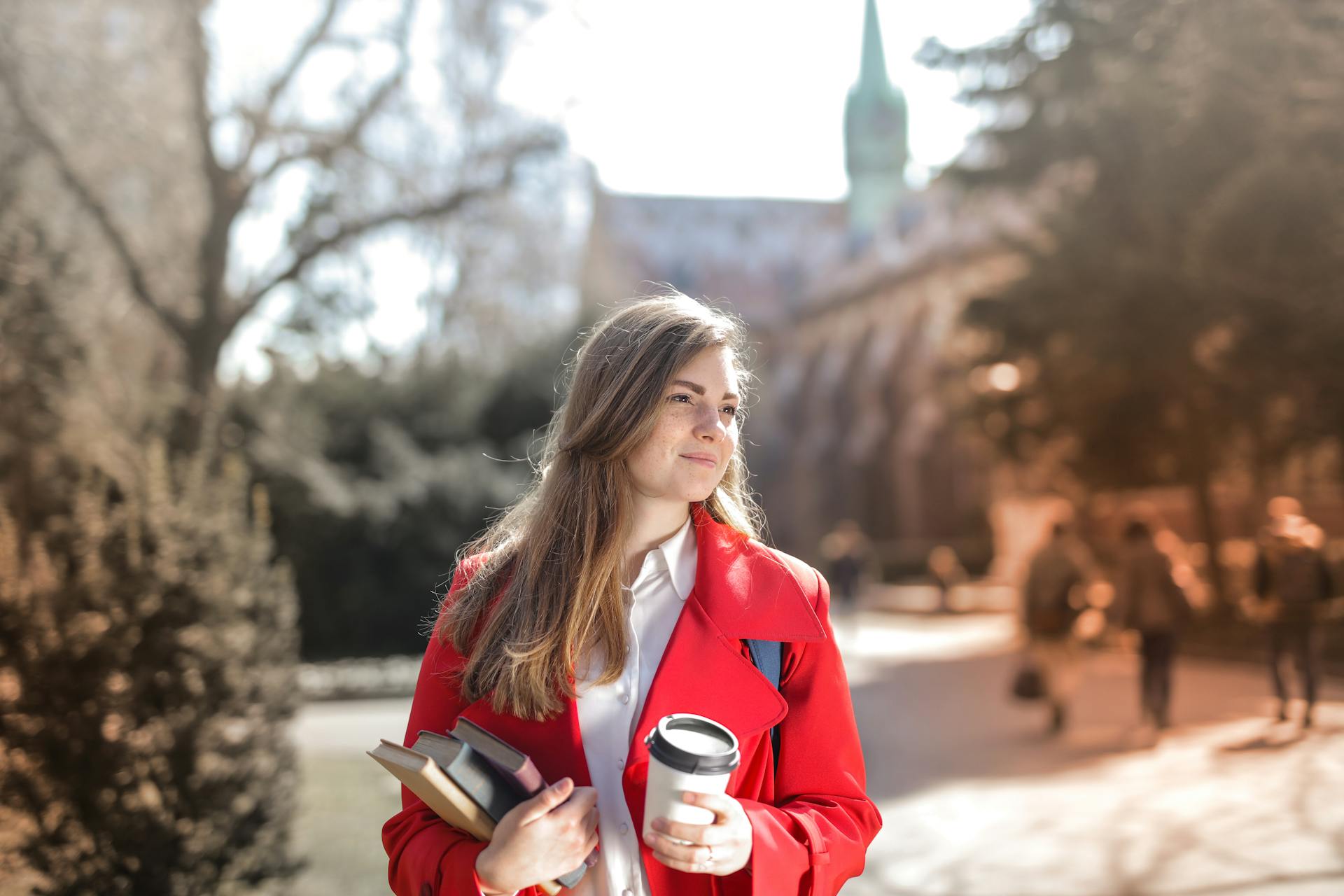 Une femme sur un campus universitaire transportant des livres | Source : Pexels