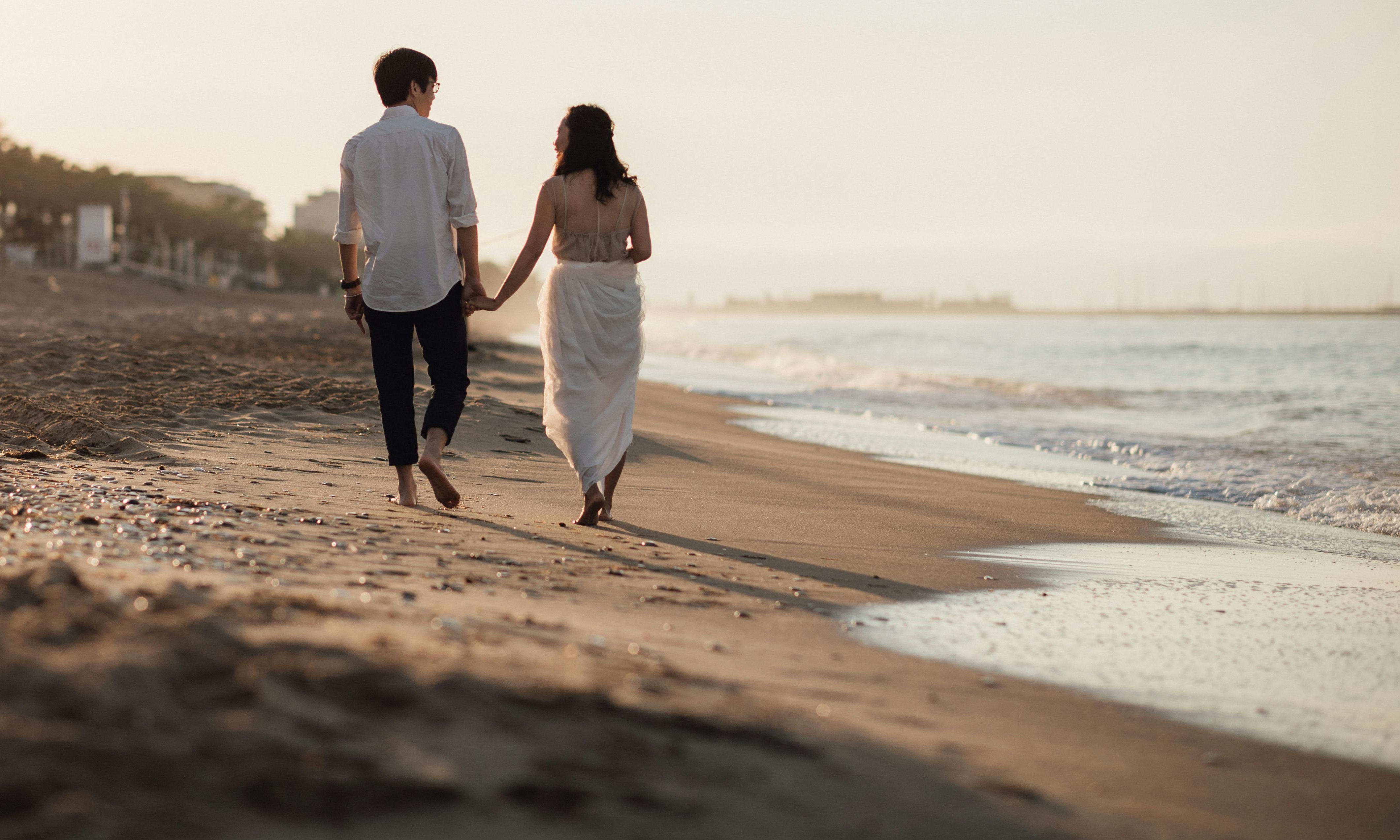 Un couple marchant main dans la main sur une plage au coucher du soleil | Source : Pexels