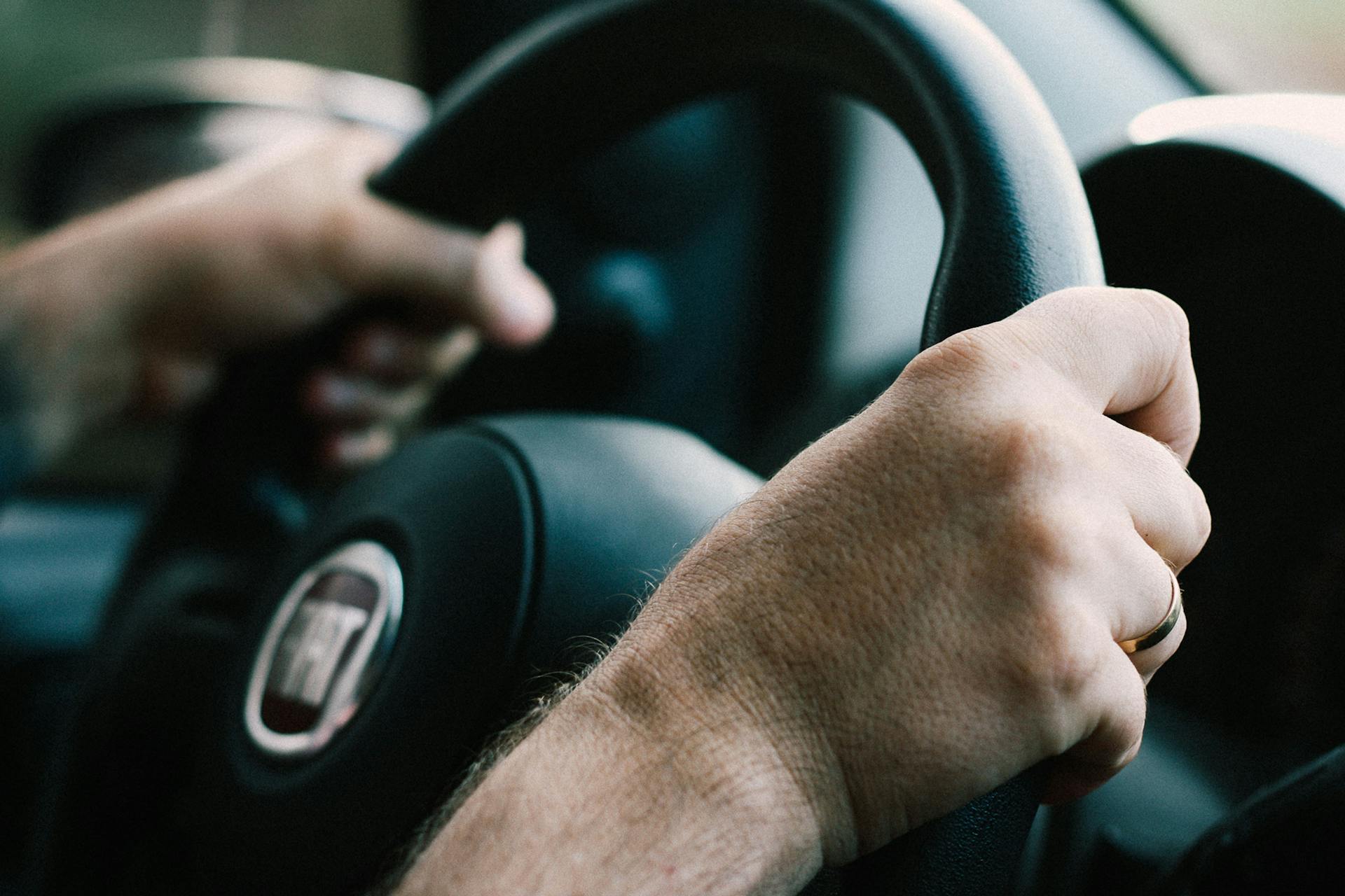 Gros plan des mains d'un homme sur un volant | Source : Pexels