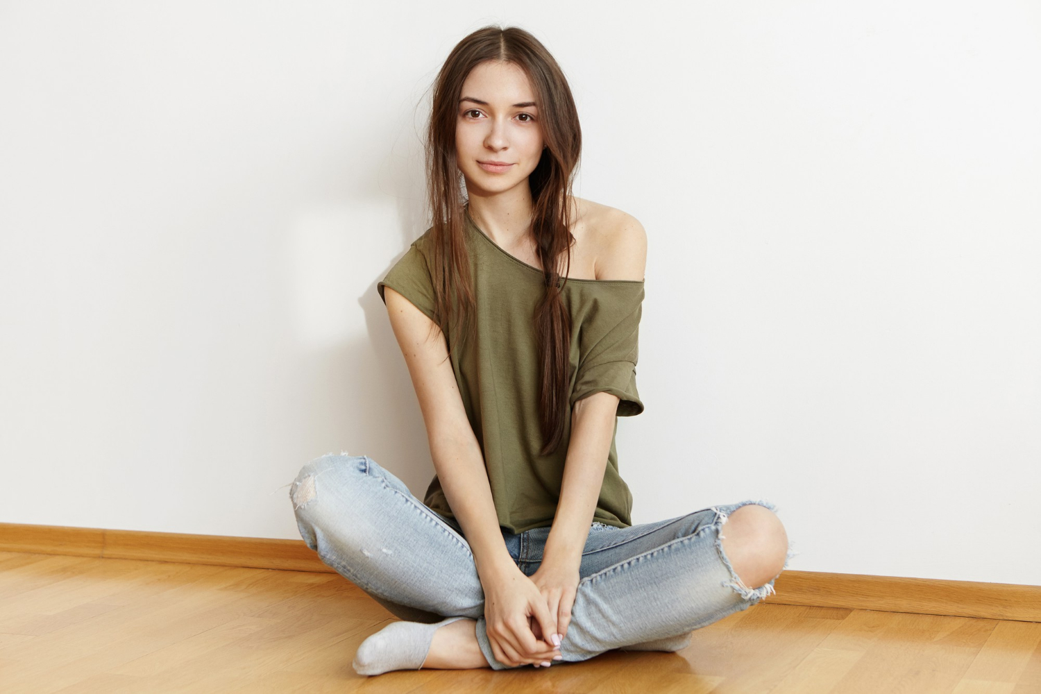 Une adolescente joyeuse assise par terre et souriante | Source : Freepik