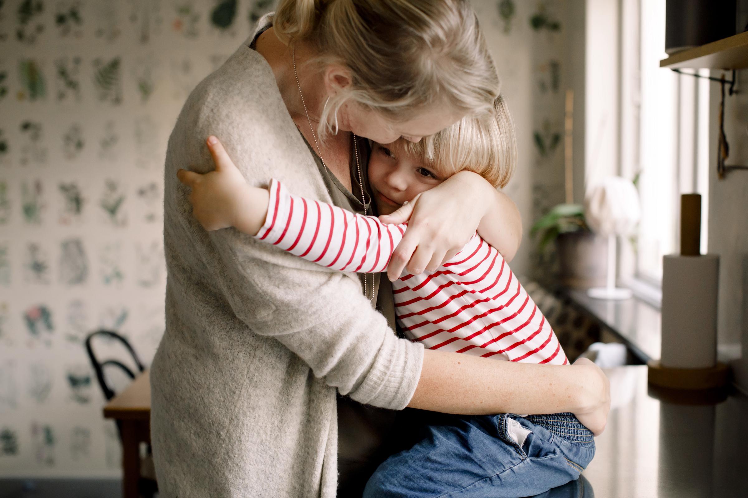 Une maman qui serre sa fille dans ses bras dans sa cuisine | Source : Getty Images