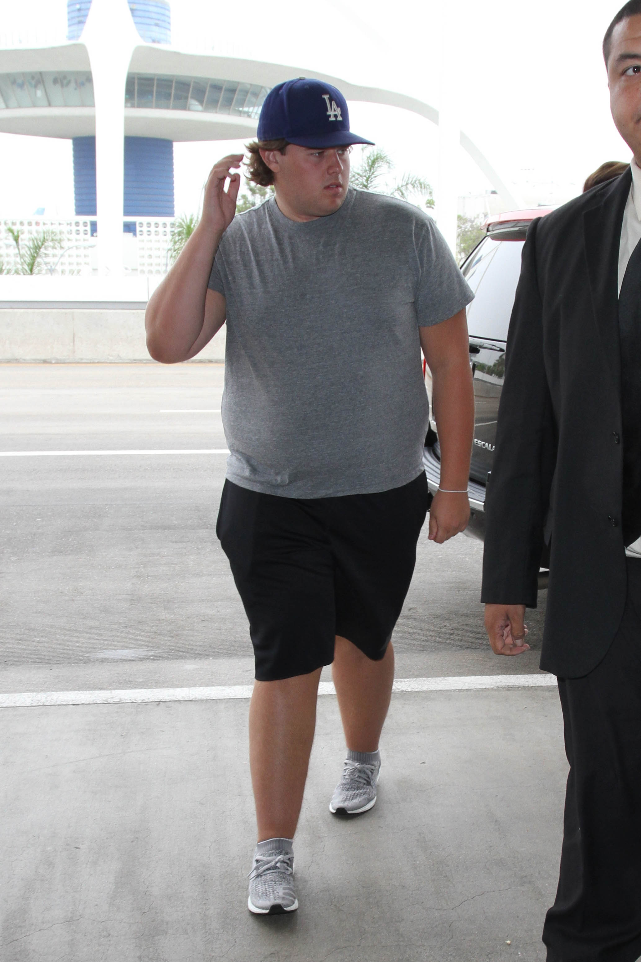 Christopher Schwarzenegger est vu à l'aéroport de Los Angeles le 31 août 2016. Vêtu d'un t-shirt gris ajusté et d'une casquette bleue des LA Dodgers, il porte un sac à dos vert et un équipement de style militaire tout en naviguant dans l'aéroport avec un cadre plus lourd et une concentration visible sur ses affaires.