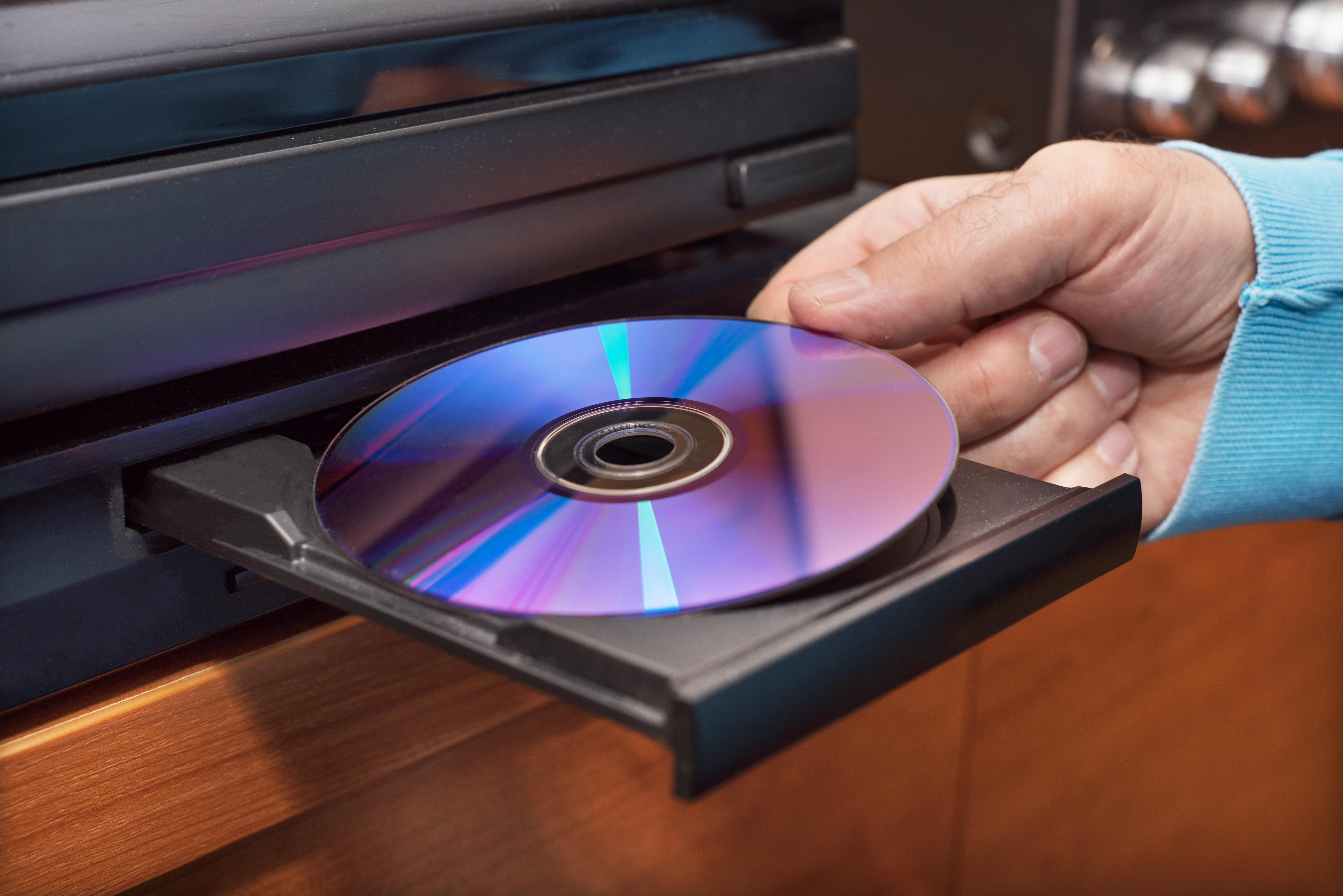 Une main plaçant un DVD dans le lecteur | Source : Shutterstock