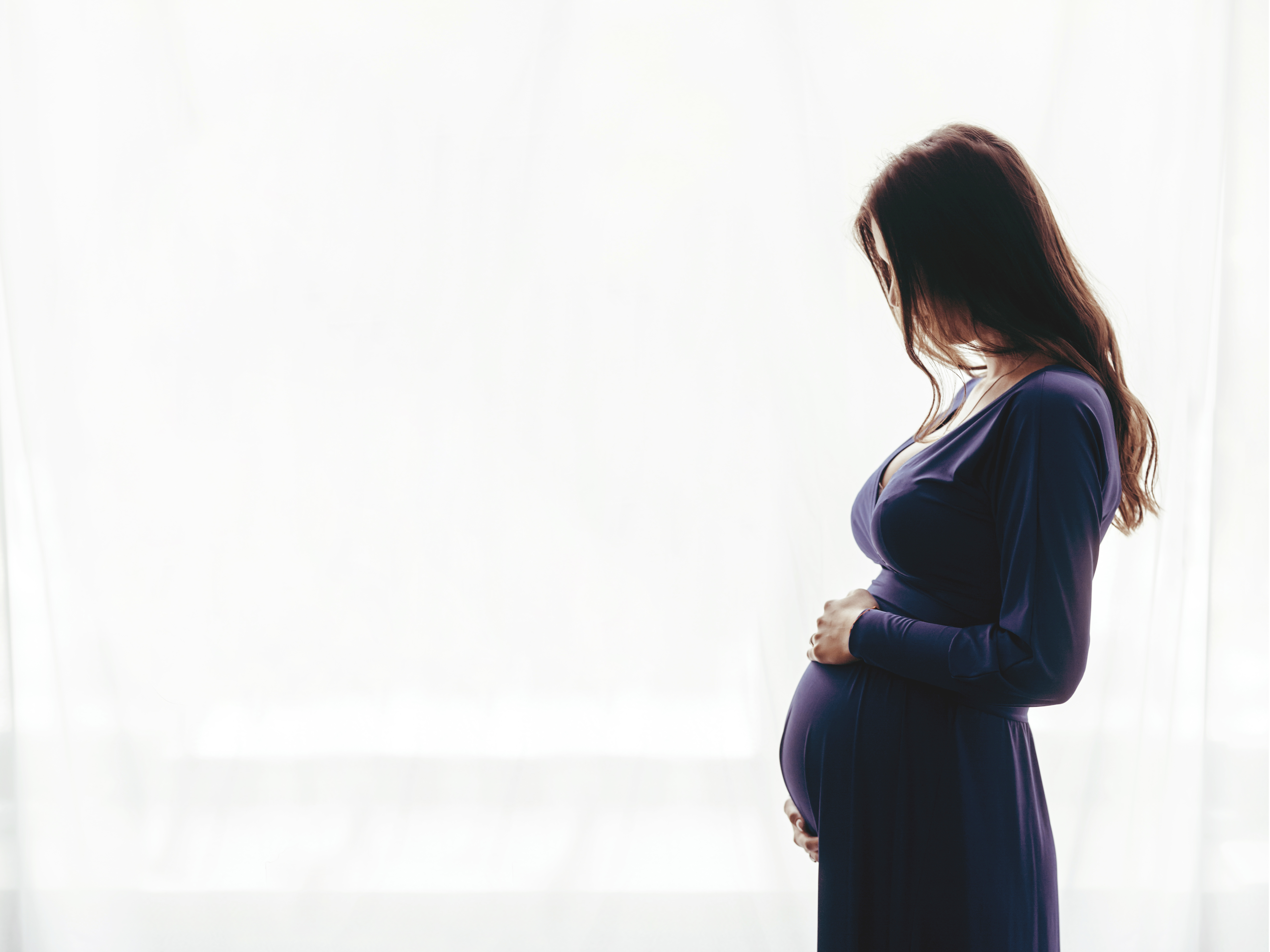 Une femme enceinte debout près d'une fenêtre | Source : Shutterstock