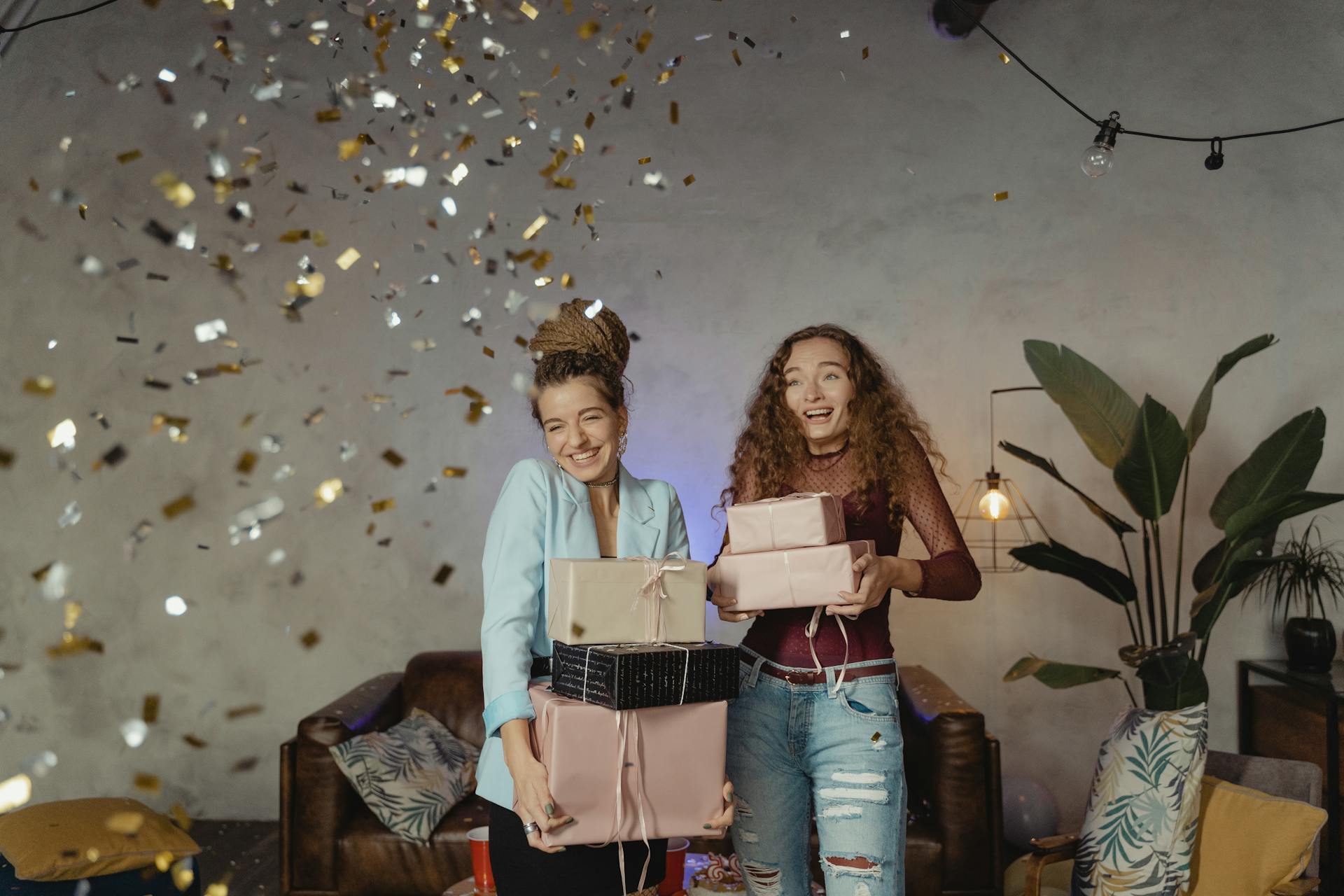 Jeunes femmes heureuses tenant des cadeaux empilés | Source : Pexels