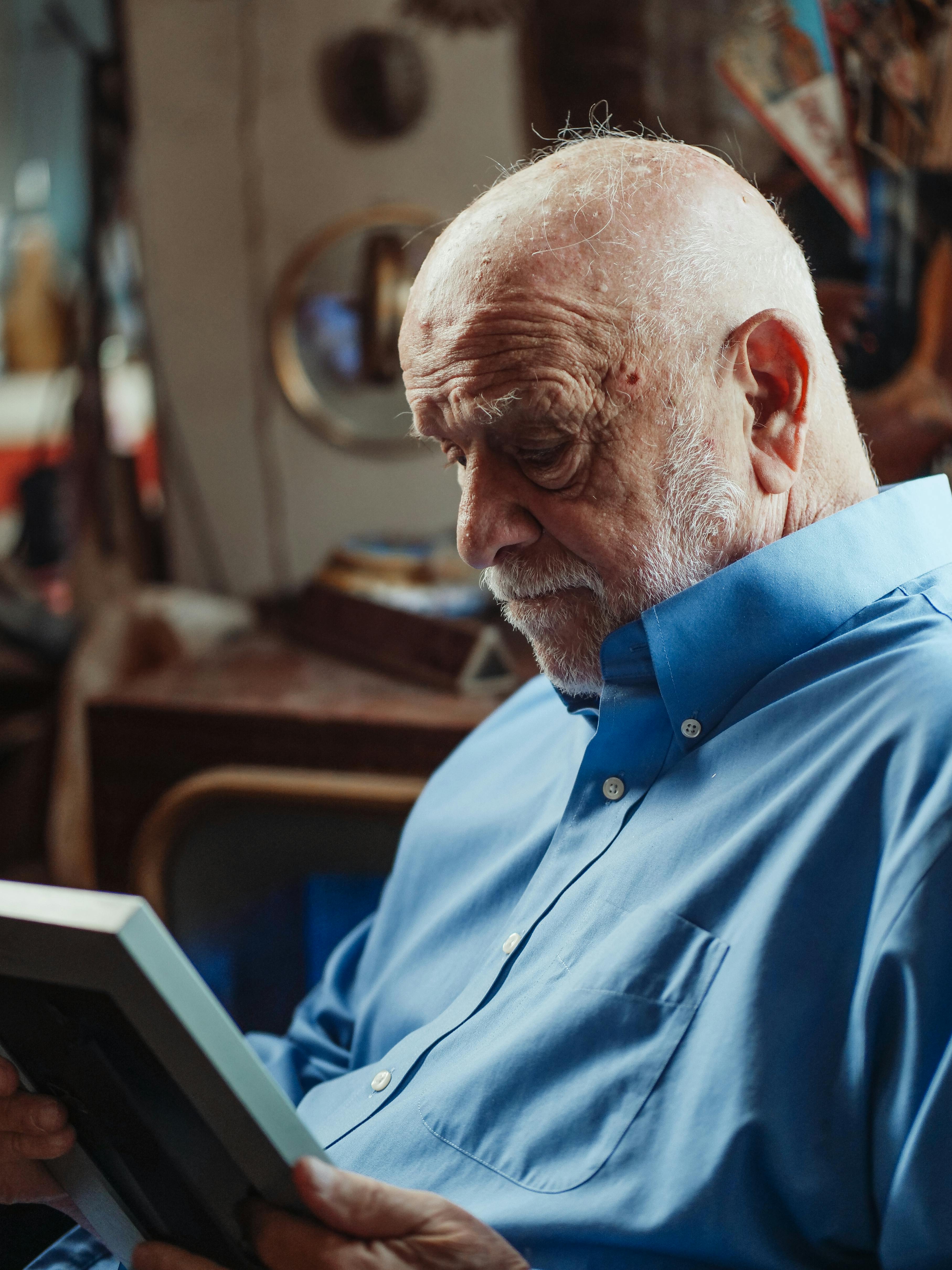 Un homme âgé fixant un cadre photo | Source : Pexels